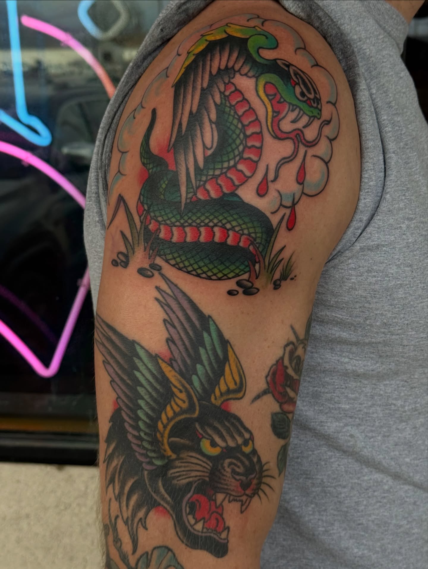 Snake and bird American traditional tattoo on the upper arm by Ben Karnofsky