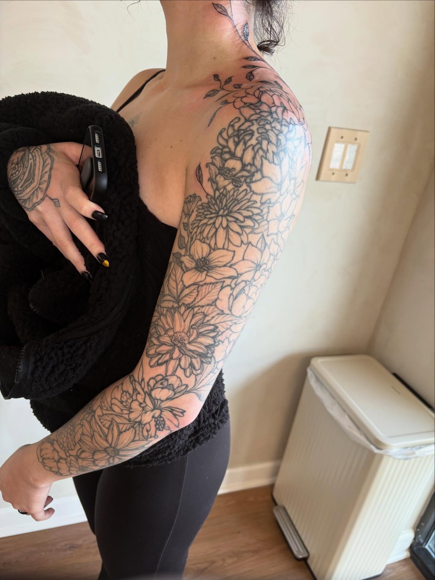 Floral black and grey tattoo on the upper arm by Dallas Davis