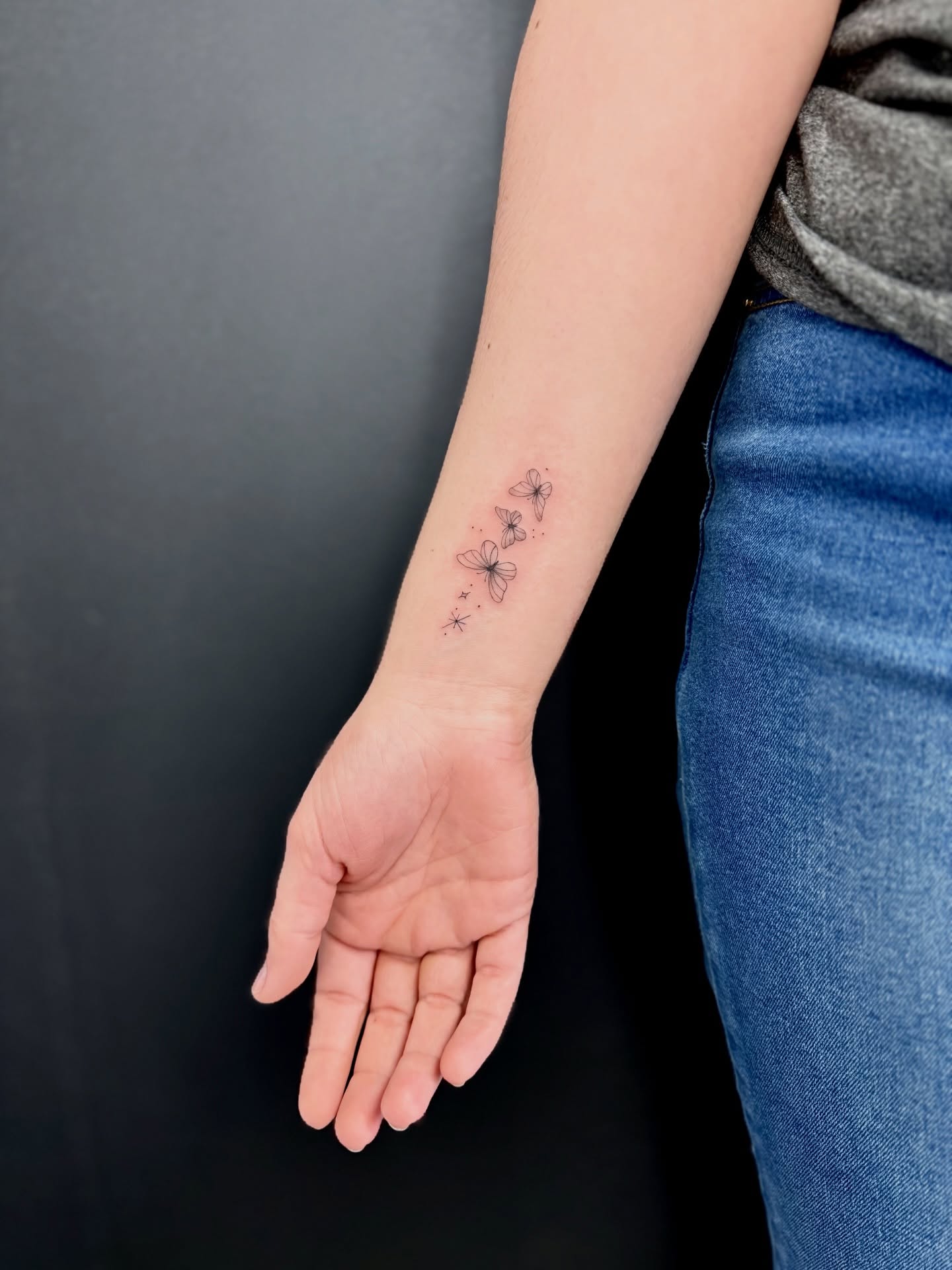 Flowers fine line tattoo on the forearm by Reverie Studio