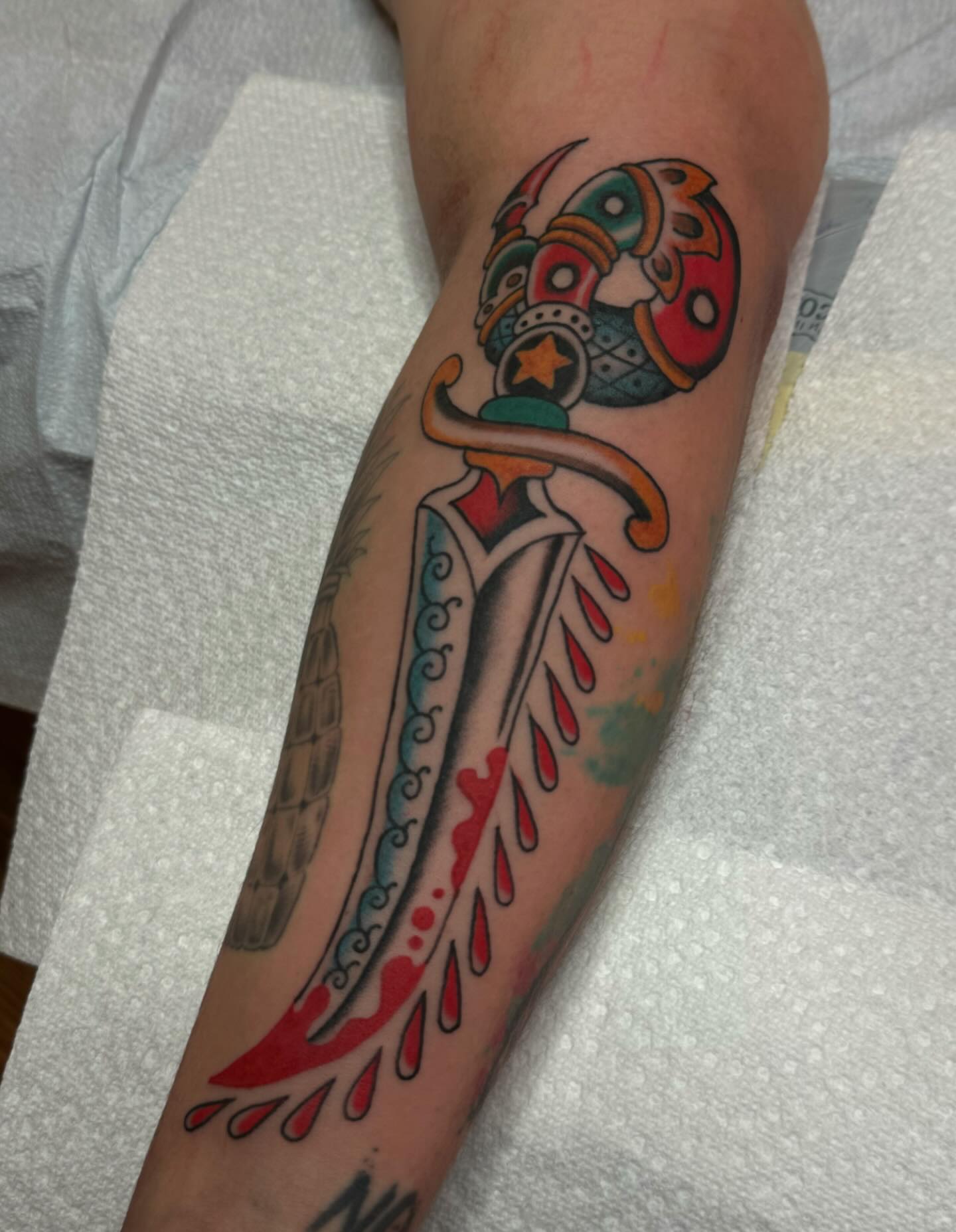 Mask and dagger American traditional tattoo on the forearm by B