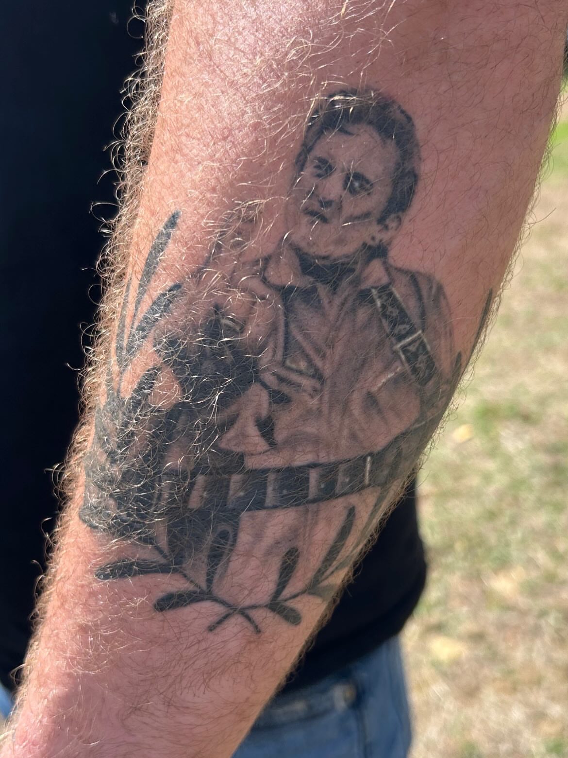 Man playing guitar black and grey tattoo on the forearm by Alex Lang