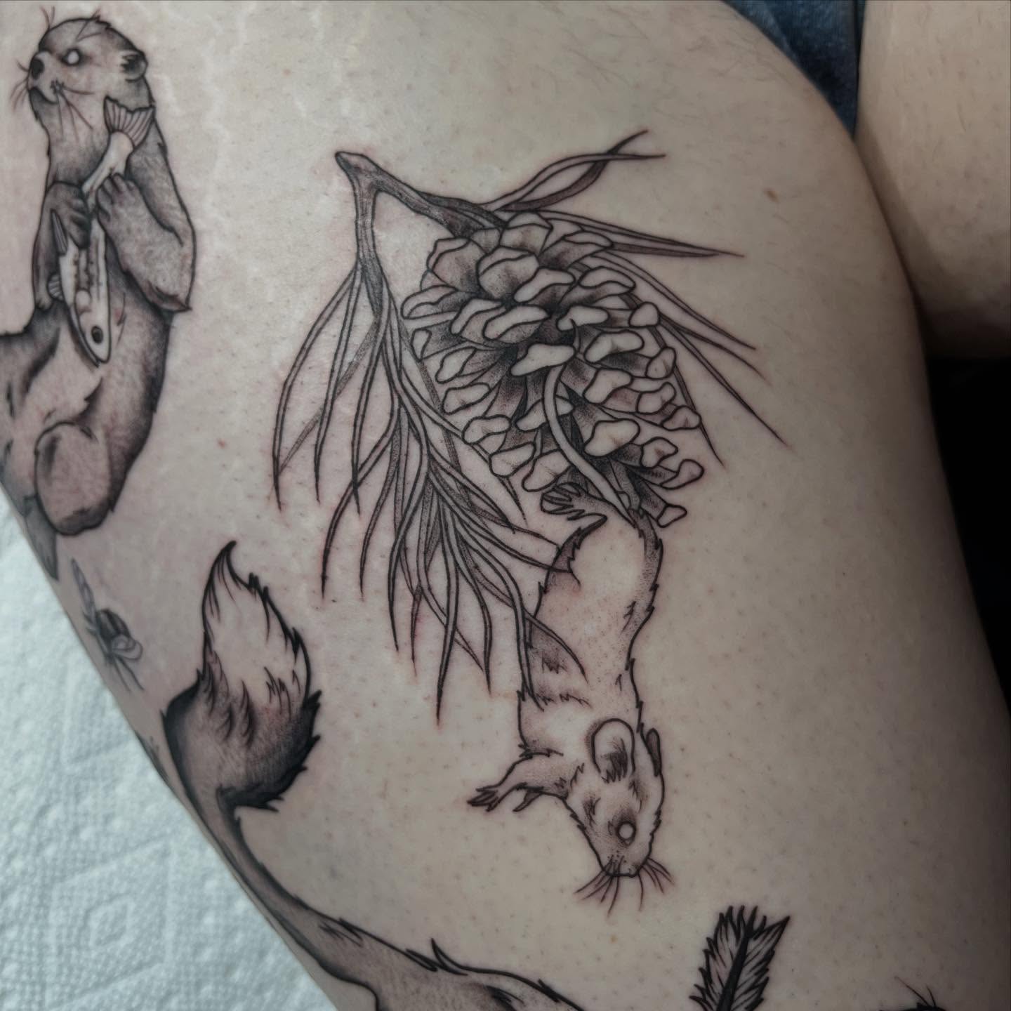 Seaweed and otter black and grey tattoo on the thigh by Ty’s Tattoos