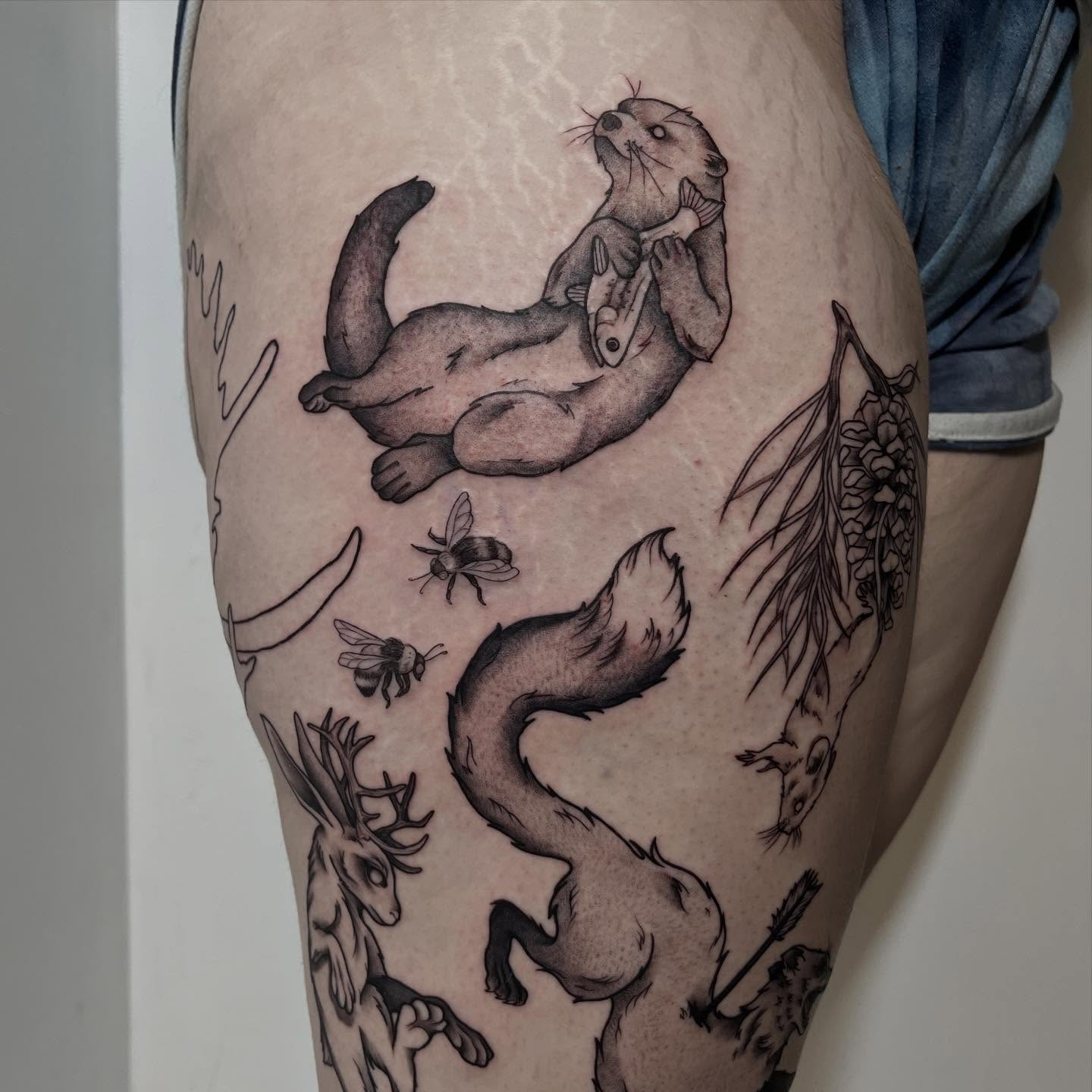 Otter and fish black and grey tattoo on the thigh by Ty’s Tattoos