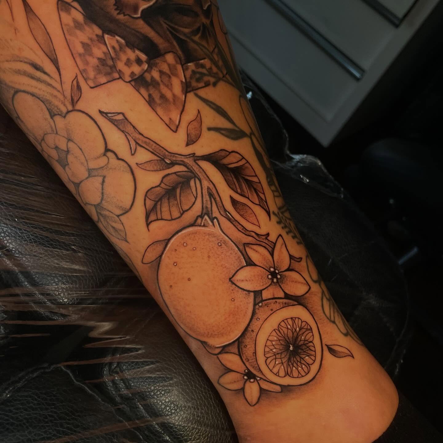 Citrus fruit and flowers realism tattoo on the forearm by Lauren Sisouphanh, Canton, Ohio