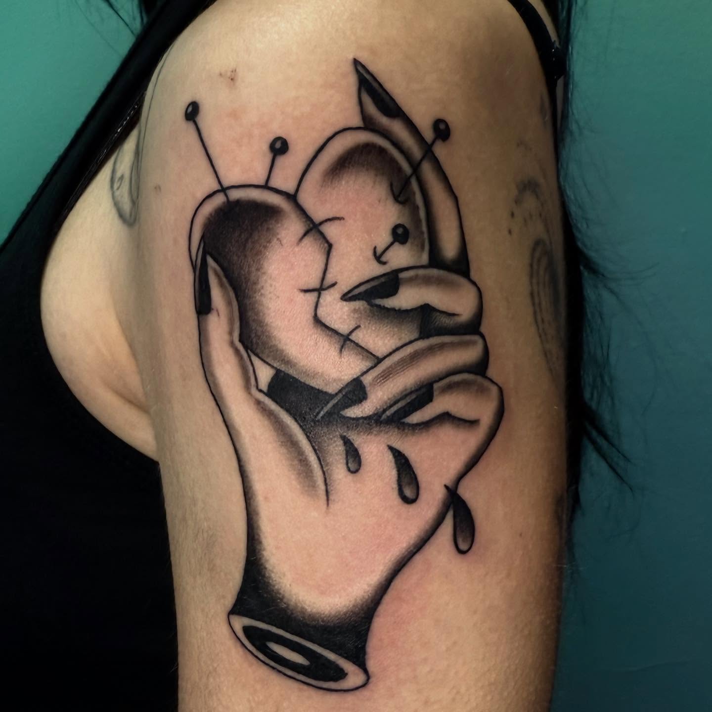Hugging cartoon characters black and grey tattoo on the upper arm by Rigo Vargas