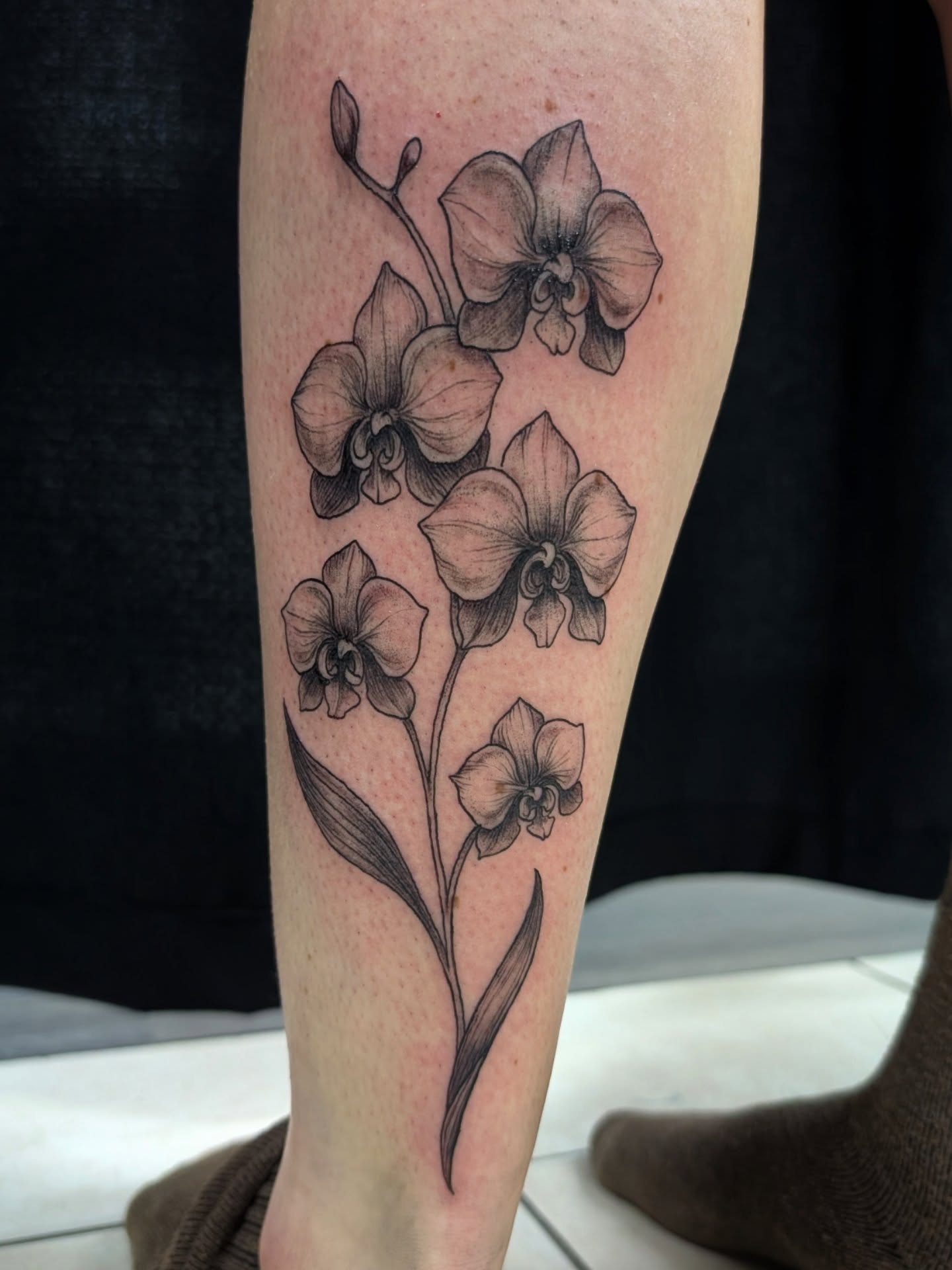 Orchids black and grey tattoo on the forearm by Katherine