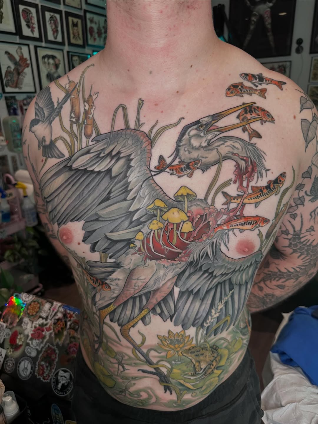 Heron eating fish in a pond fine line tattoo on the chest by Cassidy Depew, Seattle, Washington