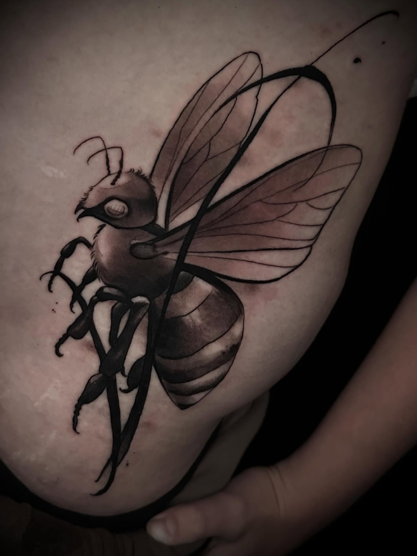 Bee black and grey tattoo on the upper arm by Nathan Adsit