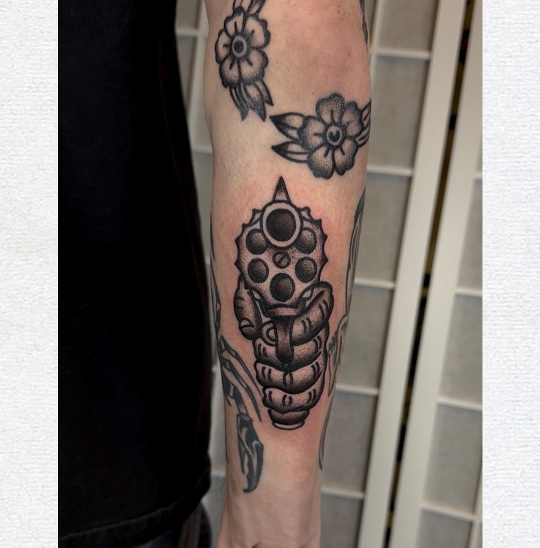 Hand holding grenade black and grey tattoo on the forearm by Vlad Nemirovsky Tattoo