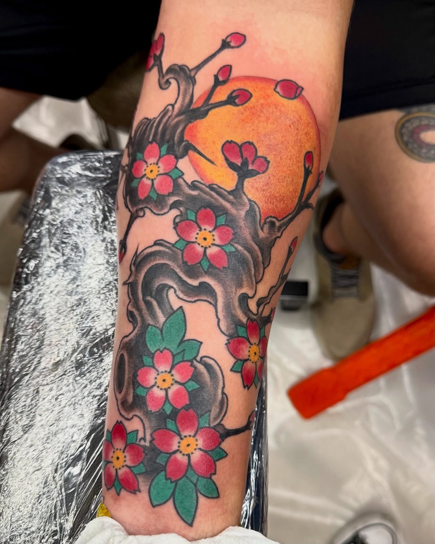 Cherry blossoms and sun American traditional tattoo on the forearm by Marcos Rivera, Laredo, Texas