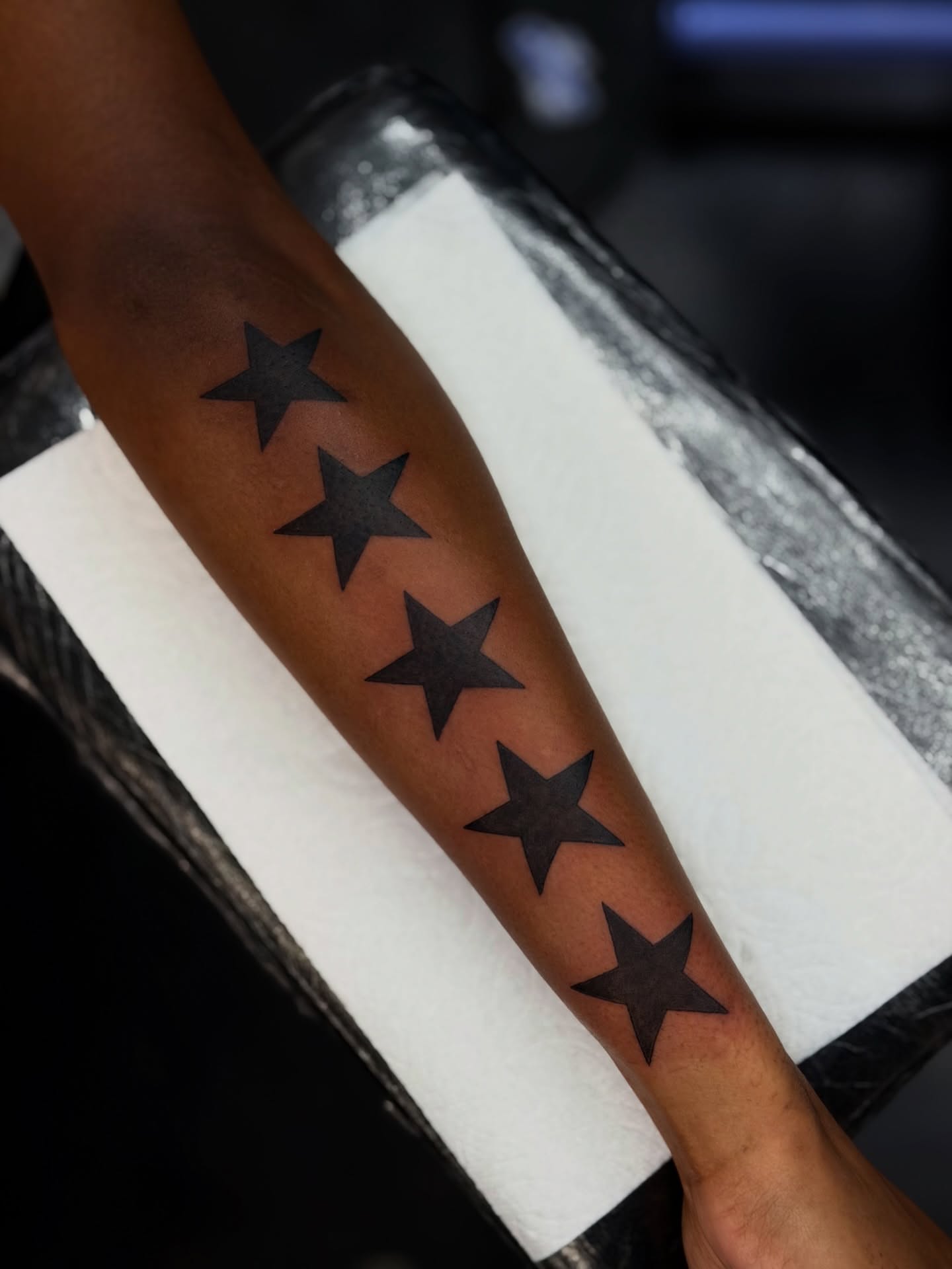 Five-pointed stars black and grey tattoo on the forearm by Bryan Nguyen