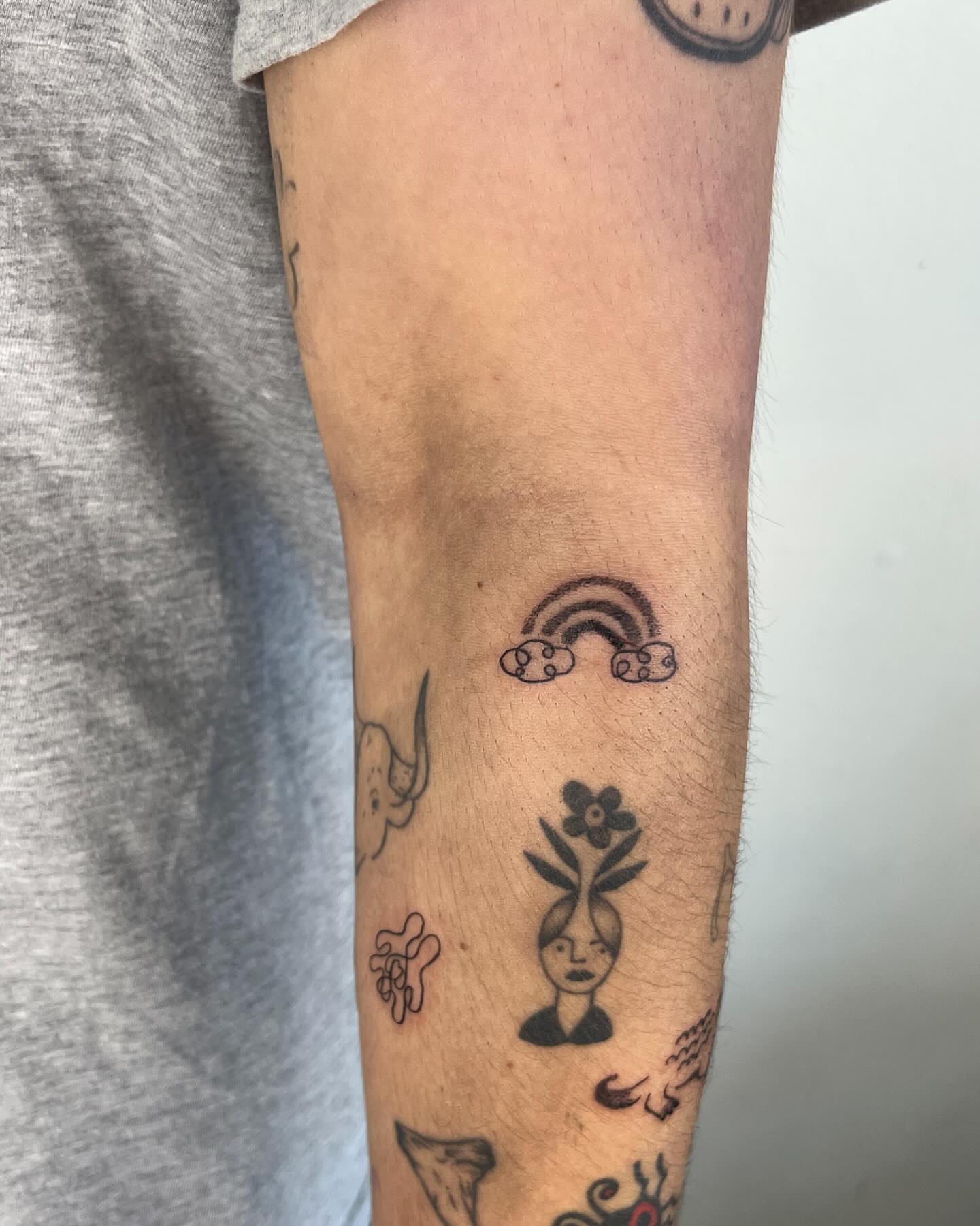 Rainbow and clouds black and grey tattoo on the forearm by luce elias :