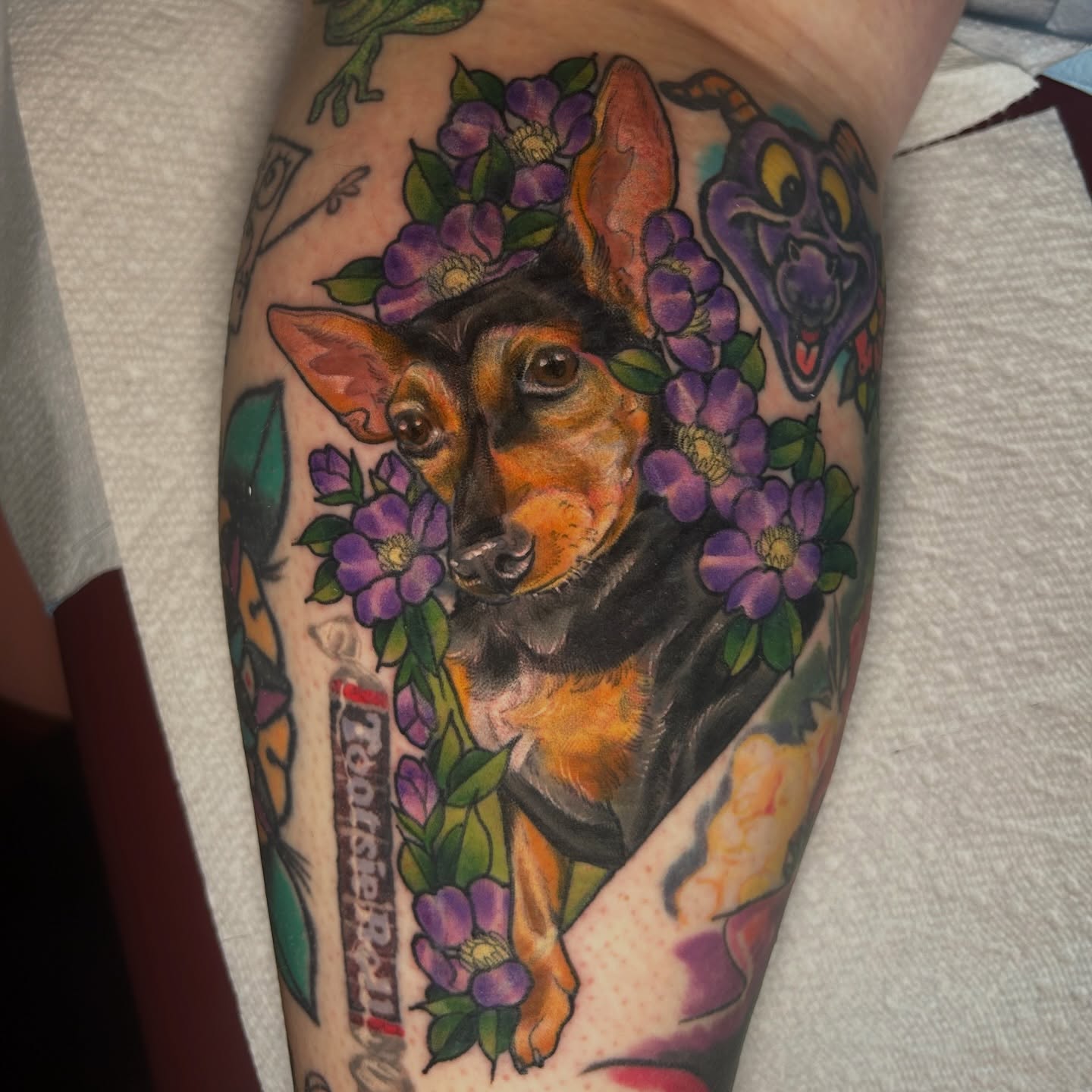 Dog with floral wreath realism tattoo on the thigh by Anna Sylvan Tattoos