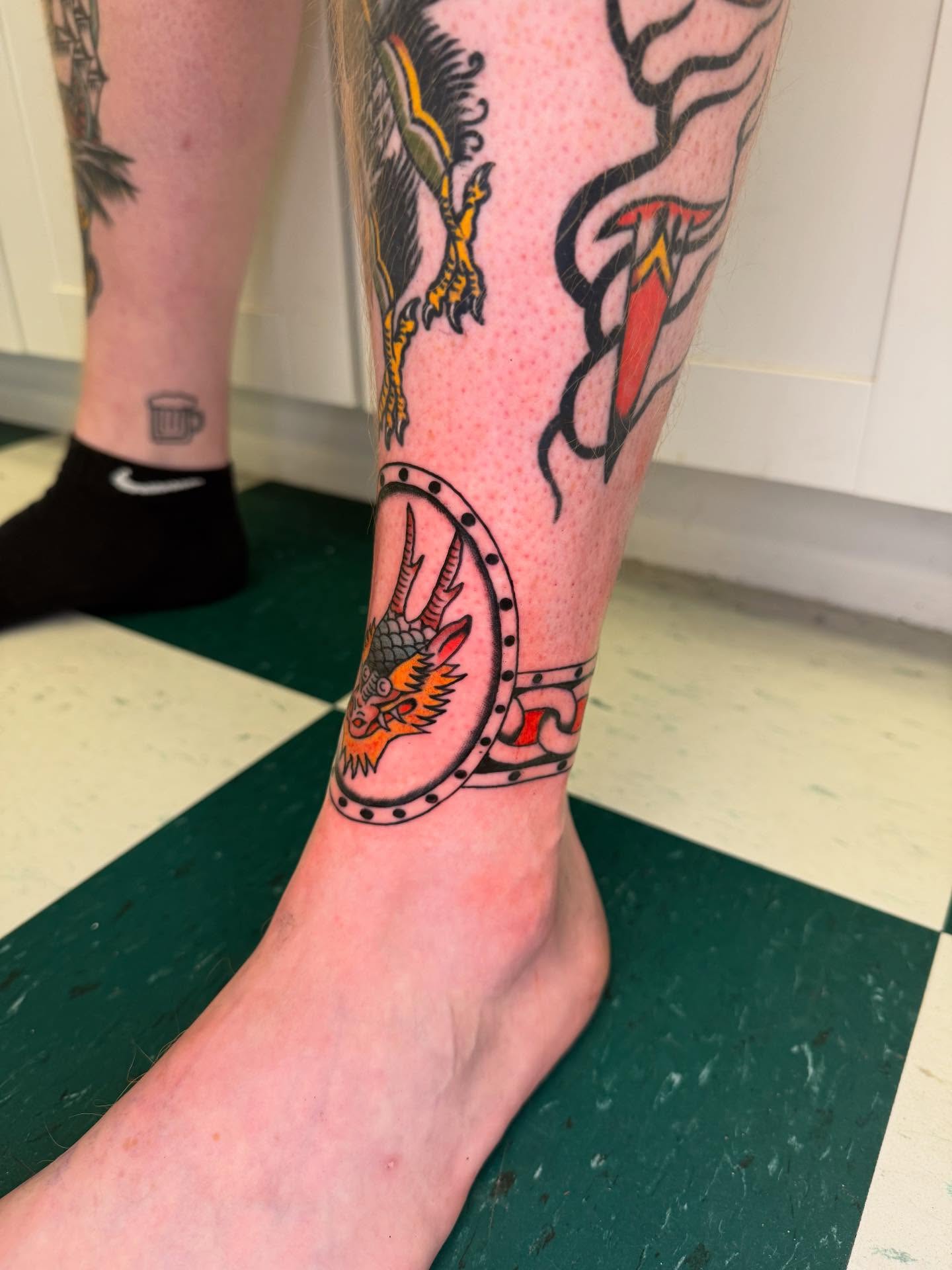 Dragon and shield American traditional tattoo on the calf by Cody Petkus