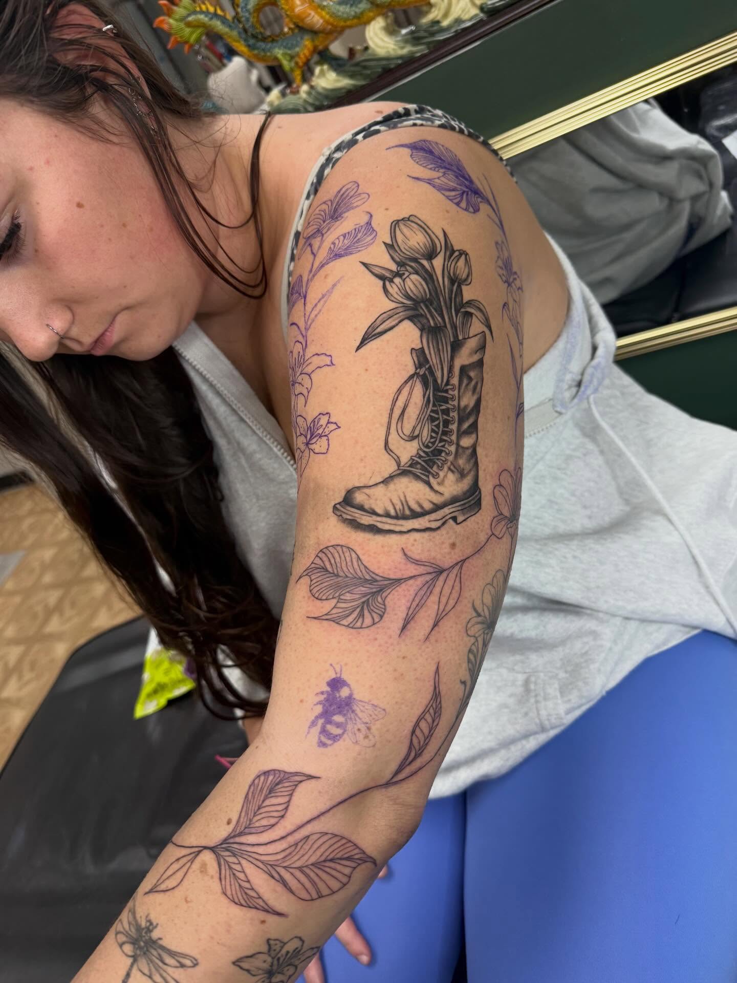 Boot with flowers black and grey tattoo on the upper arm by Imani