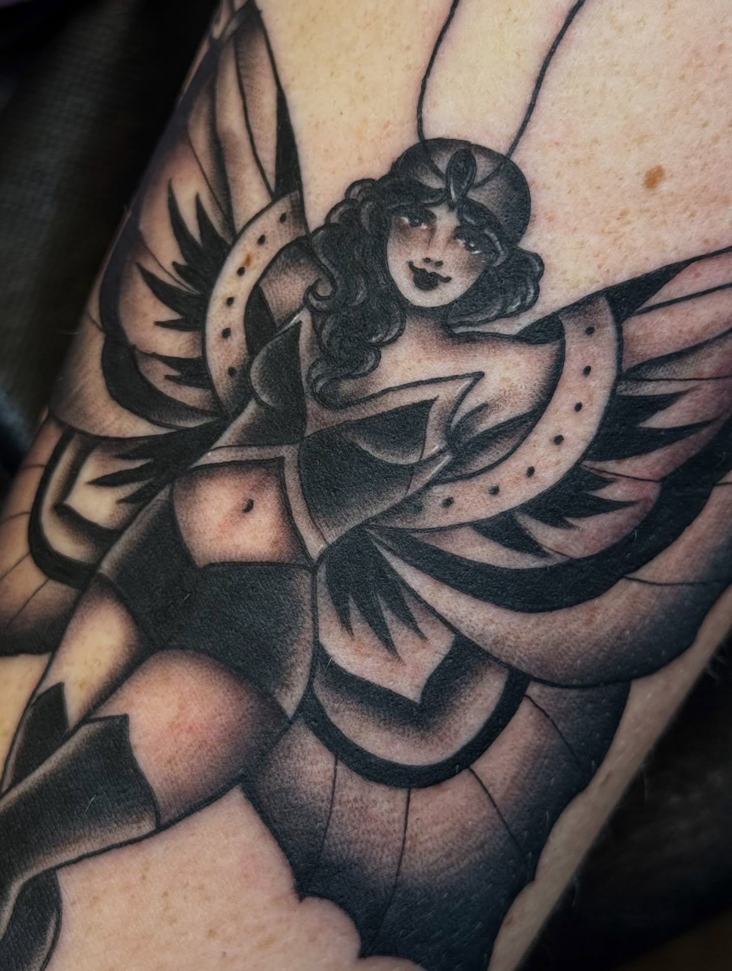 Winged woman American traditional tattoo on the upper arm by Anna Wall