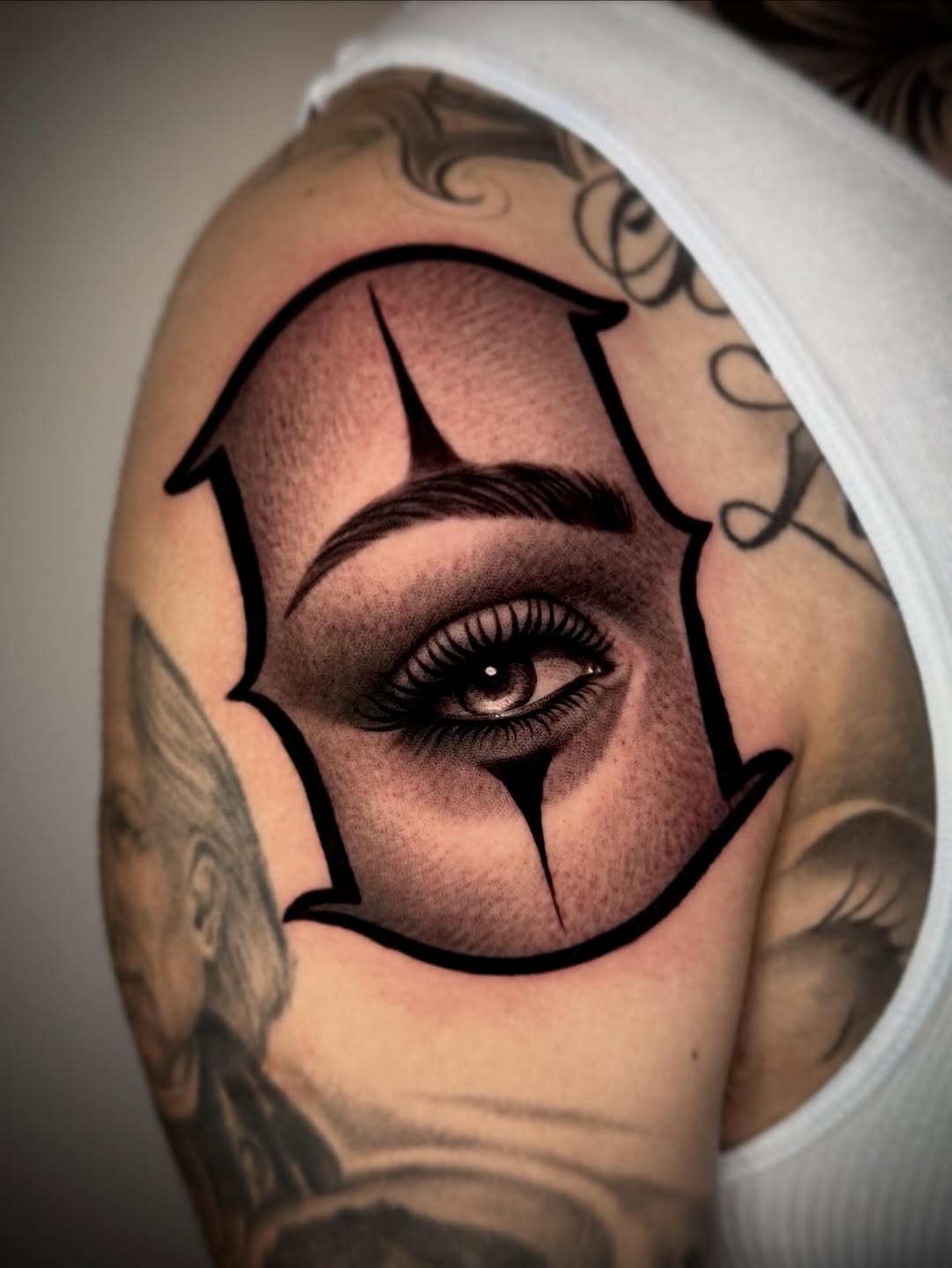 Clown eye Chicano tattoo on the shoulder by David Torres
