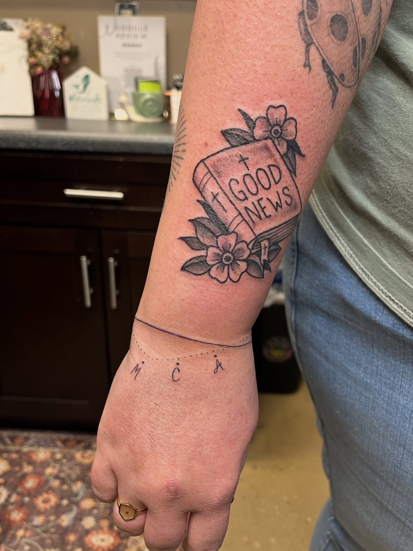 Good news book black and grey tattoo on the forearm by Tabitha Mathis