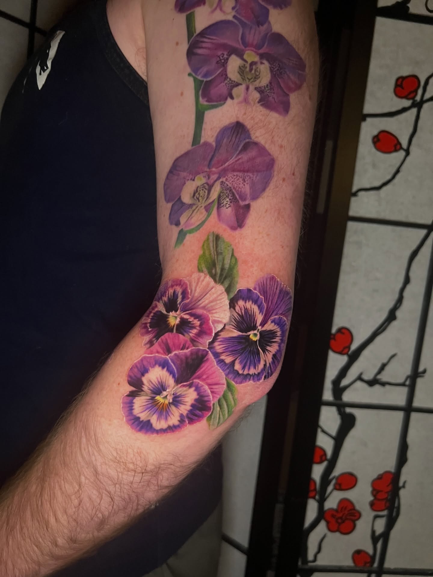 Purple orchids and pansies realism tattoo on the forearm by Belle Halverson