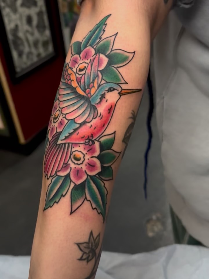 Hummingbird and flowers American traditional tattoo on the forearm by Bre