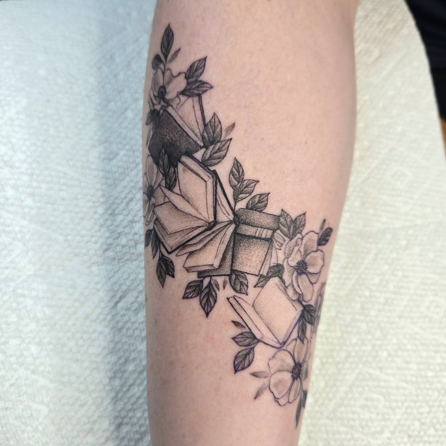 Book and flowers dotwork tattoo on the forearm by Amanda Hinrichs