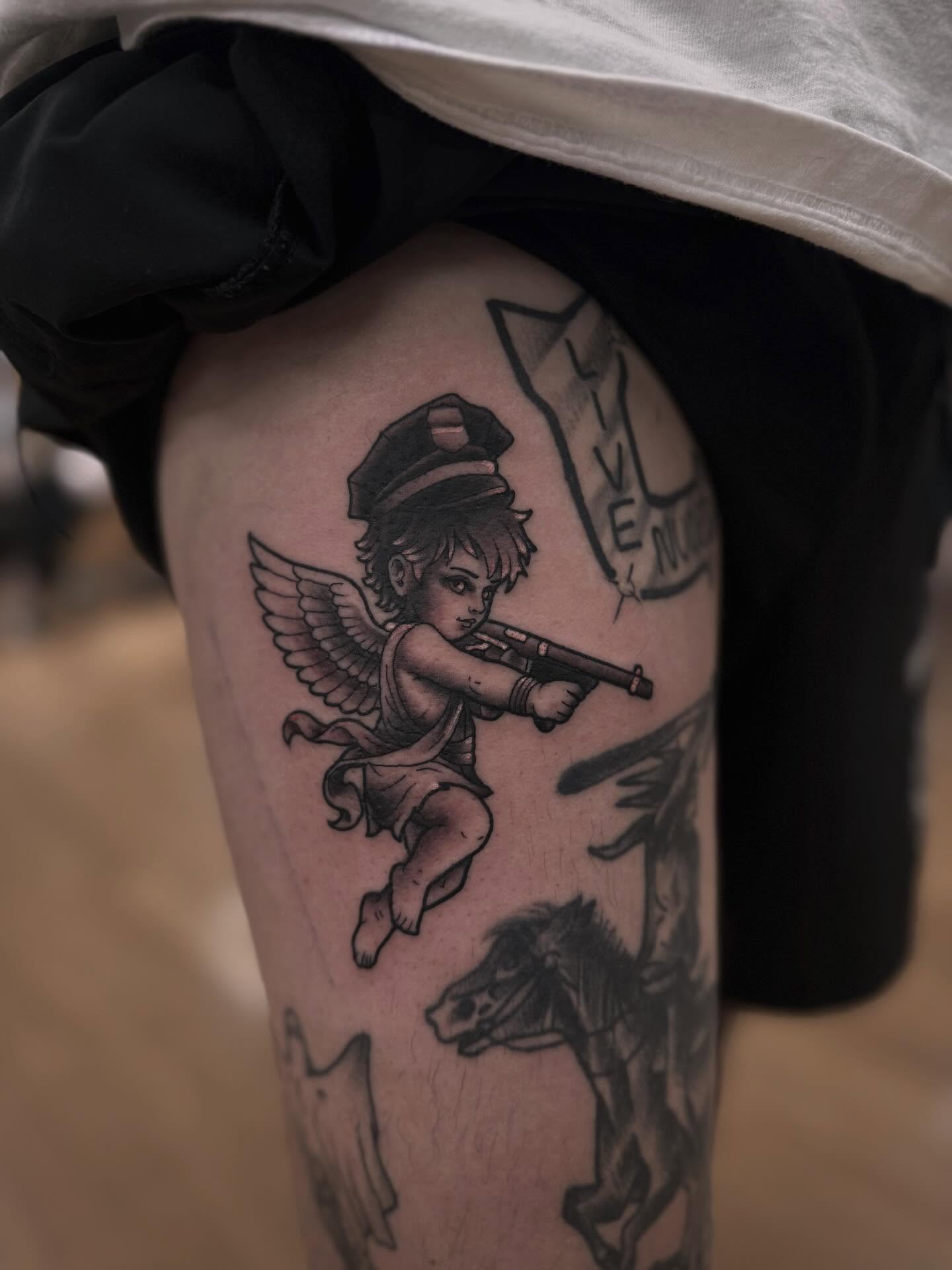 Angel with gun black and grey tattoo on the thigh by Tyler Harrington