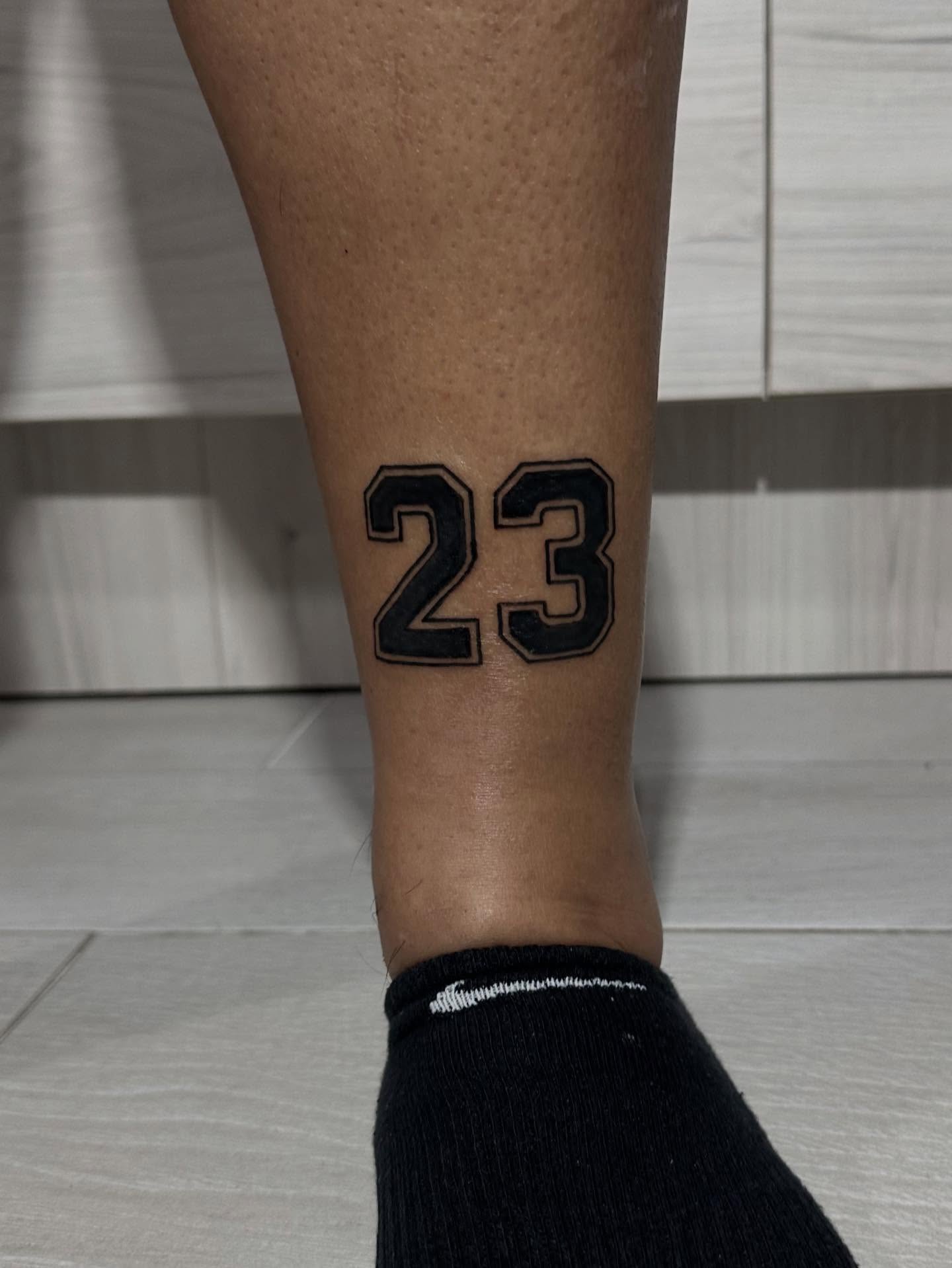 Number 23 black and grey tattoo on the calf by Kunaytattoo