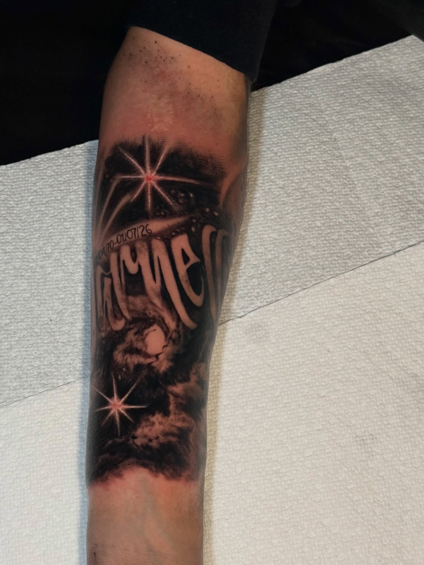 Night sky with stars and text dark realism tattoo on the forearm by Isaac