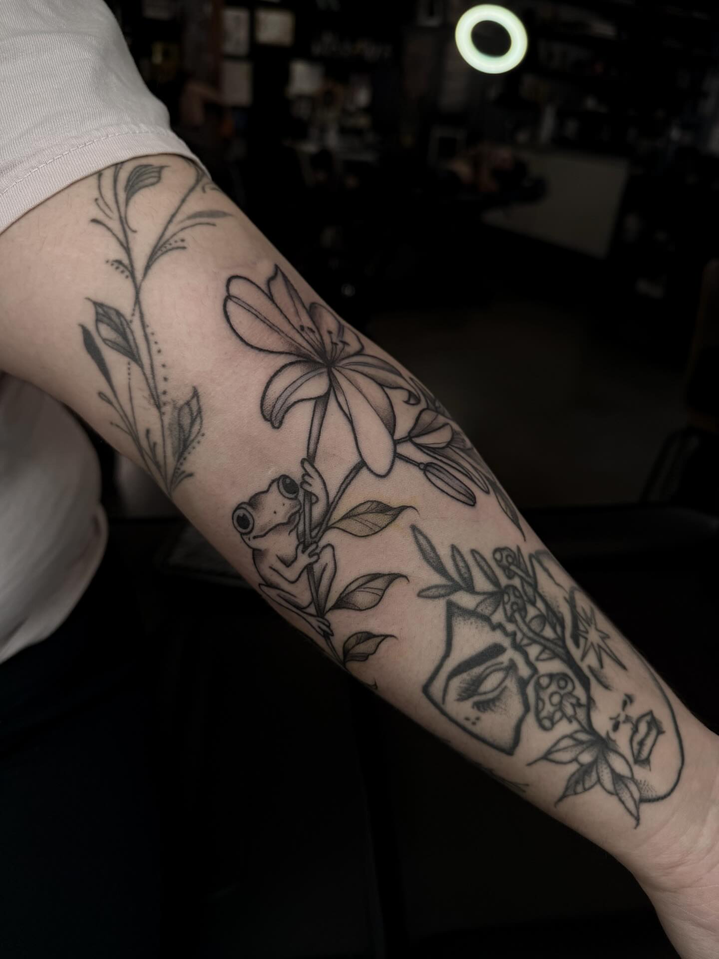 Lily and frog black and grey tattoo on the forearm by Susie Maj