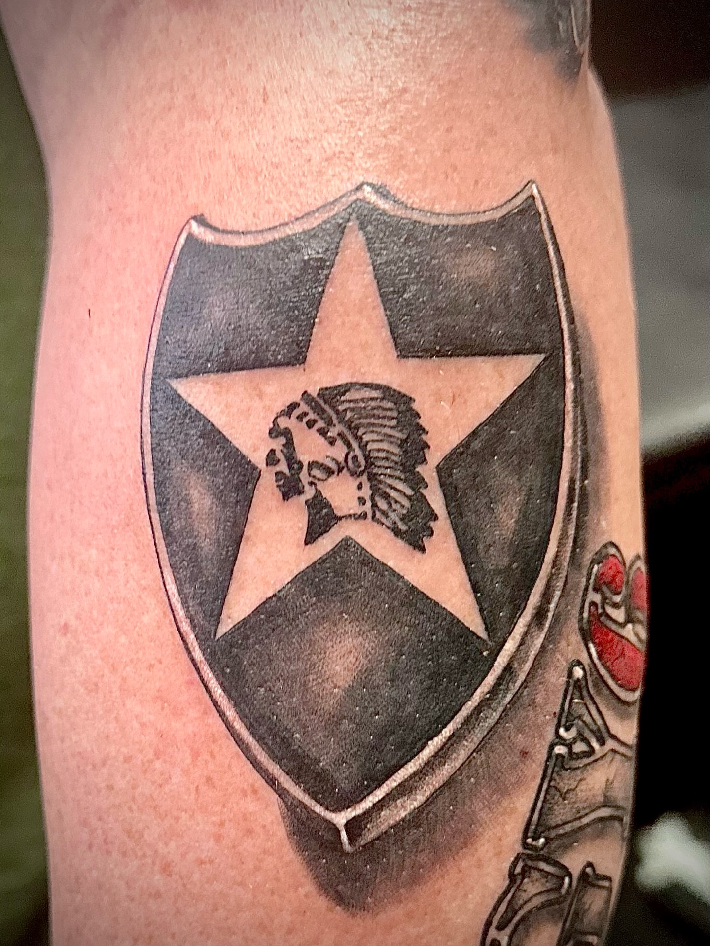 Shield with star and warrior black and grey tattoo on the forearm by Ricky Flemate, San Antonio