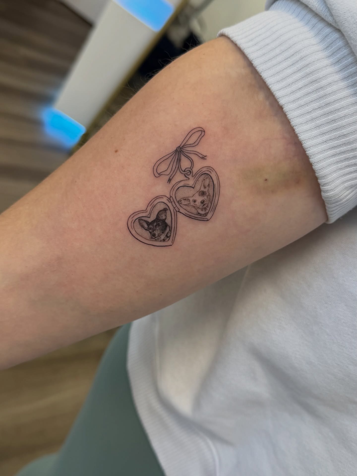 Heart-shaped locket with dog black and grey tattoo on the forearm by Daniel Montoya, Charlotte, North Carolina