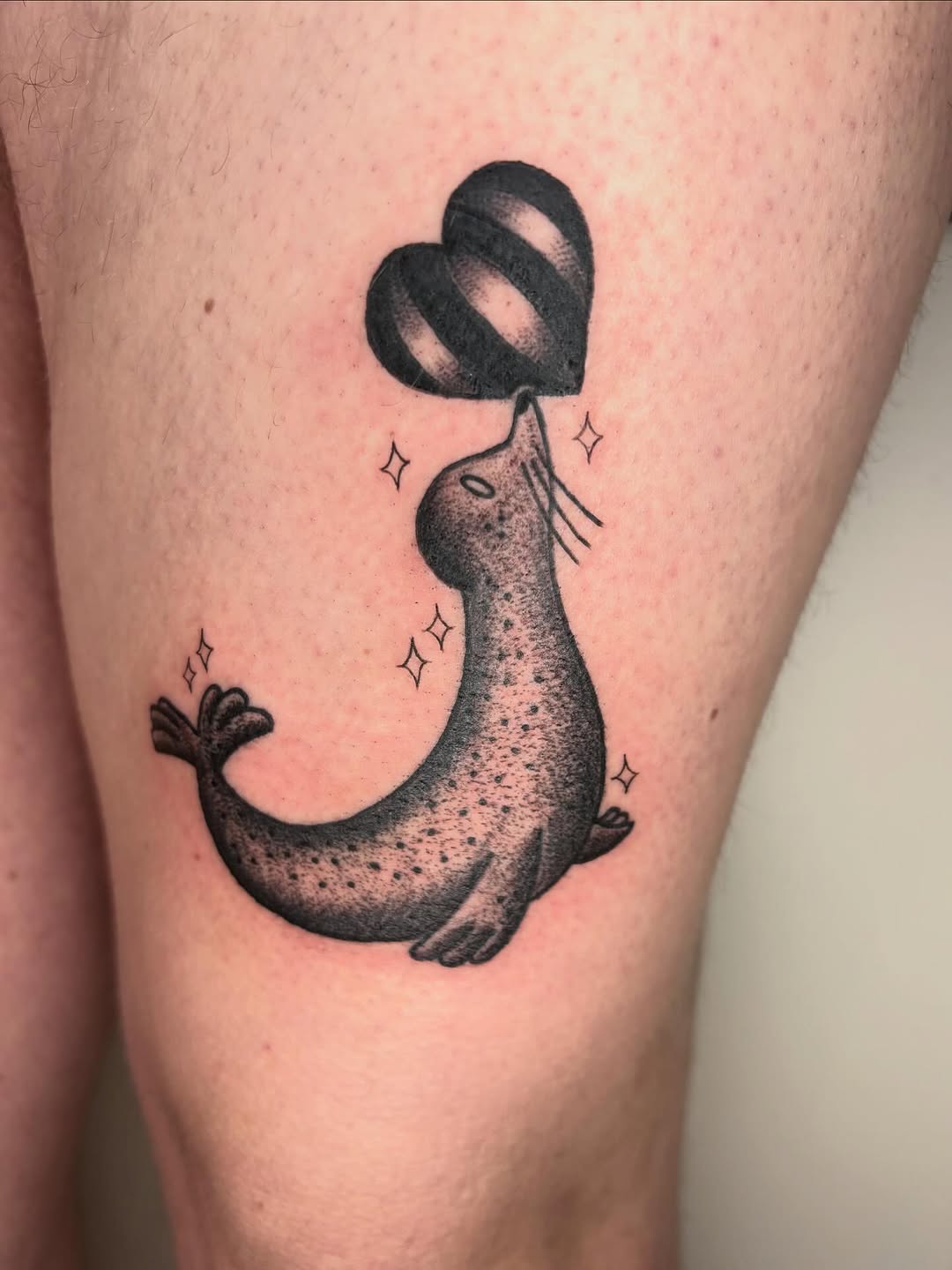 Seal holding a heart balloon fine line tattoo on the thigh by Fin :