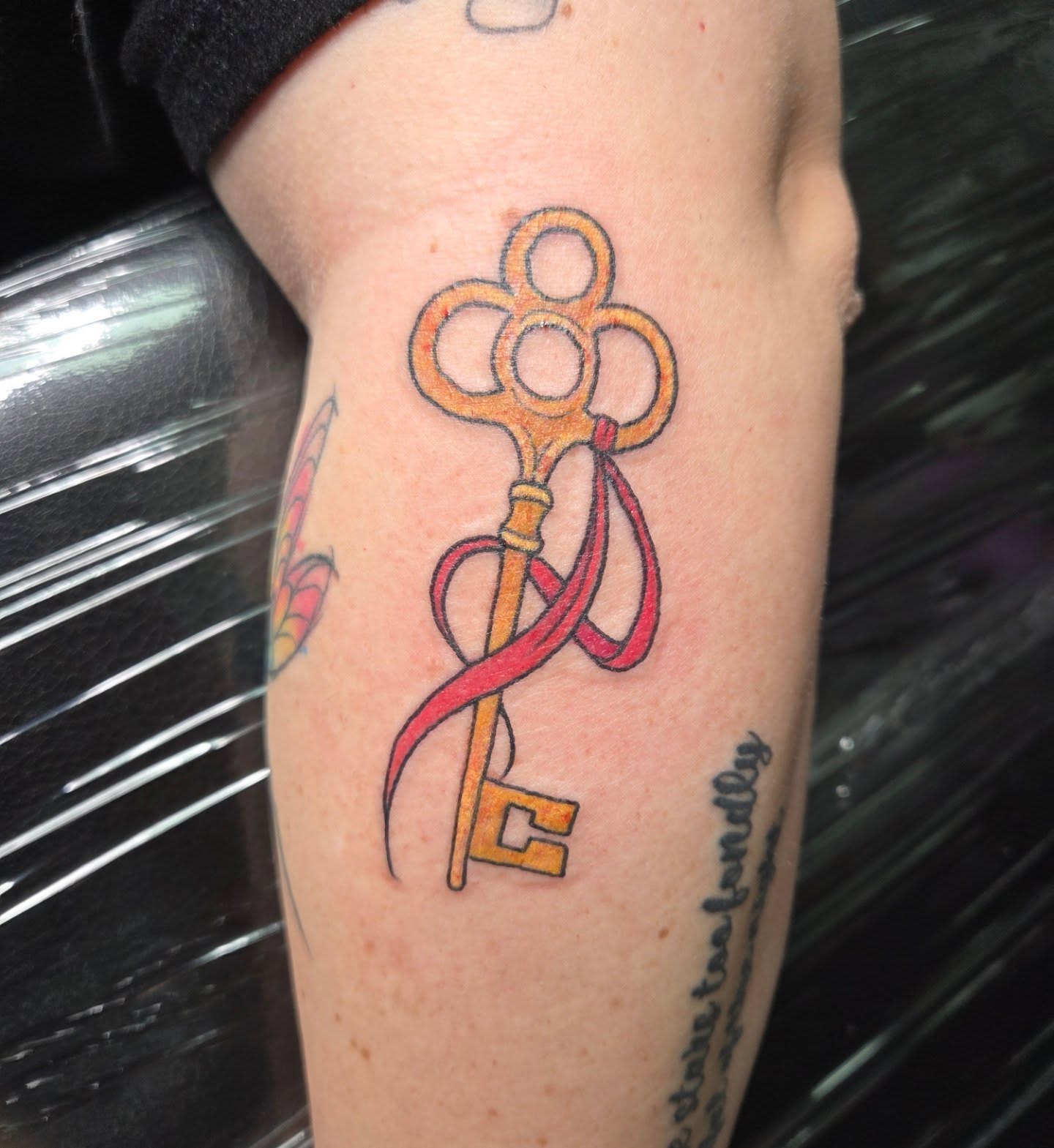 Key with ribbon new school tattoo on the forearm by Trinity Renee