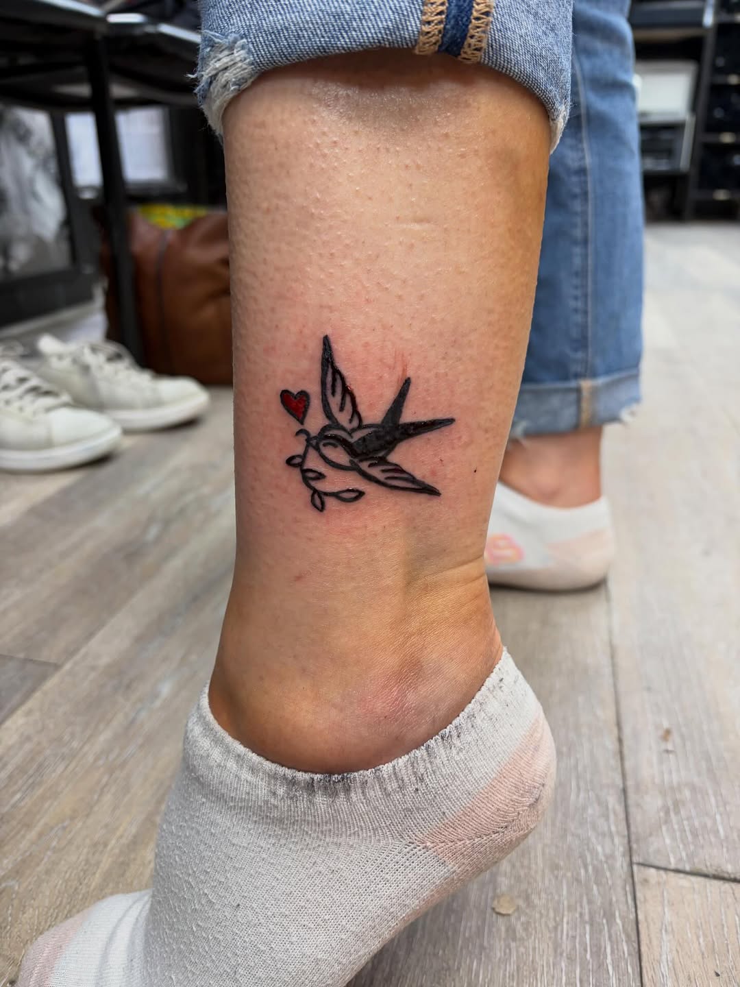 Swallow with heart and leaves fine line tattoo on the calf by Madison