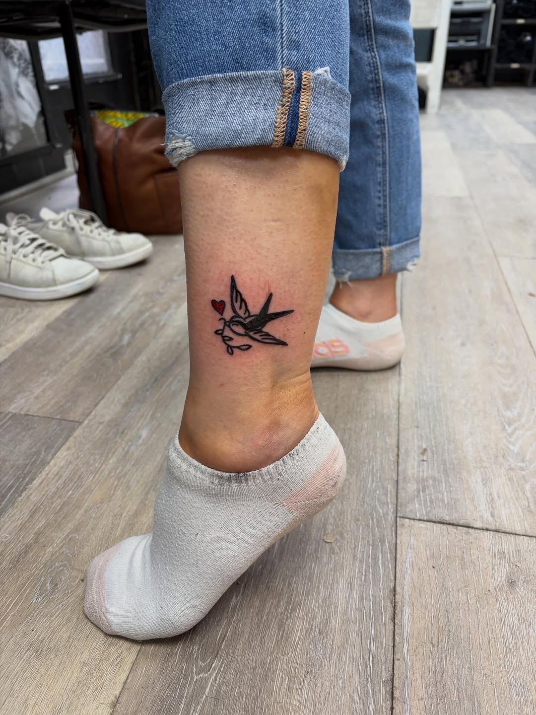 Swallow with heart and branch fine line tattoo on the foot by Madison