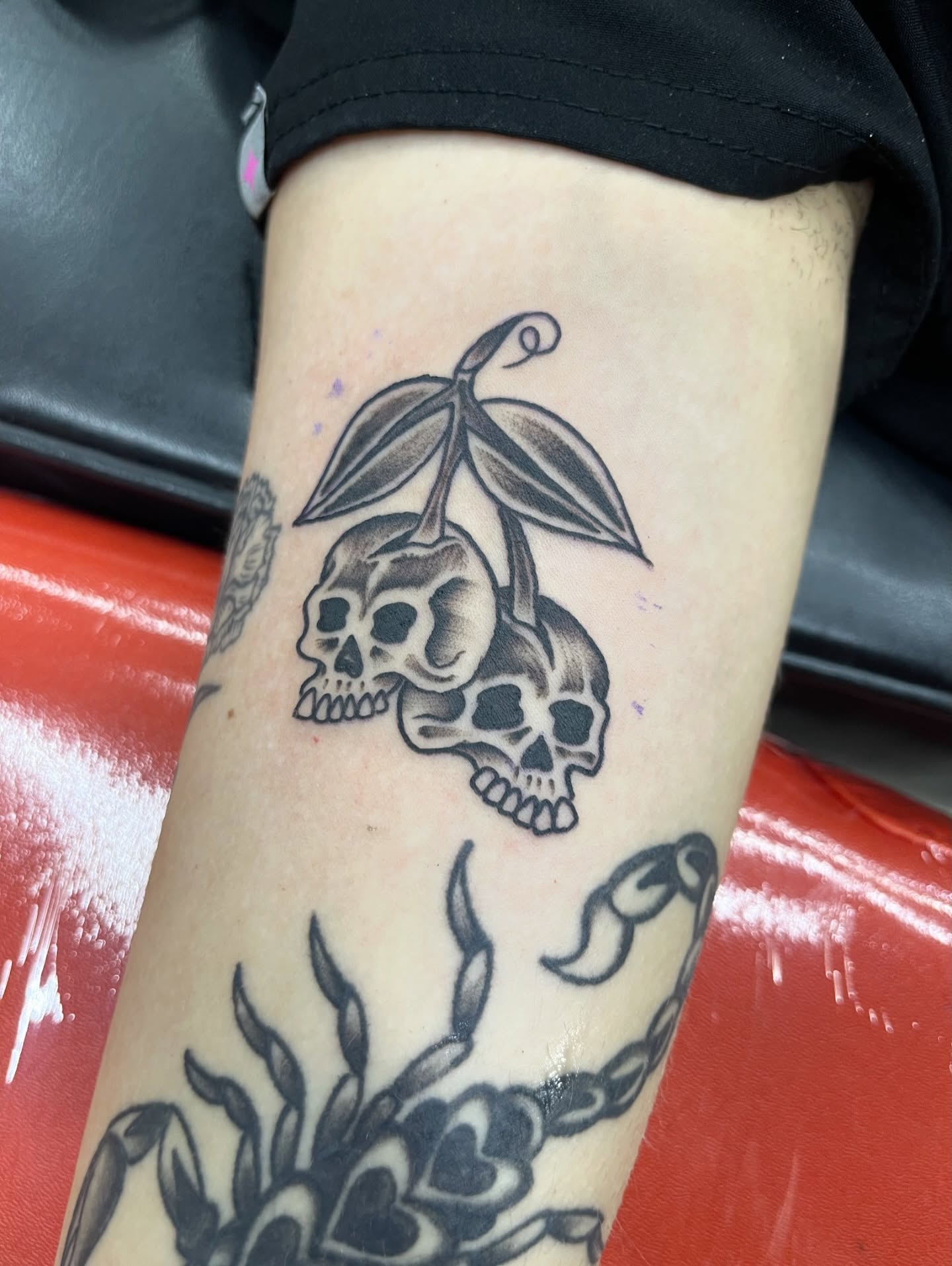 Skulls and leaves black and grey tattoo on the forearm by Squid