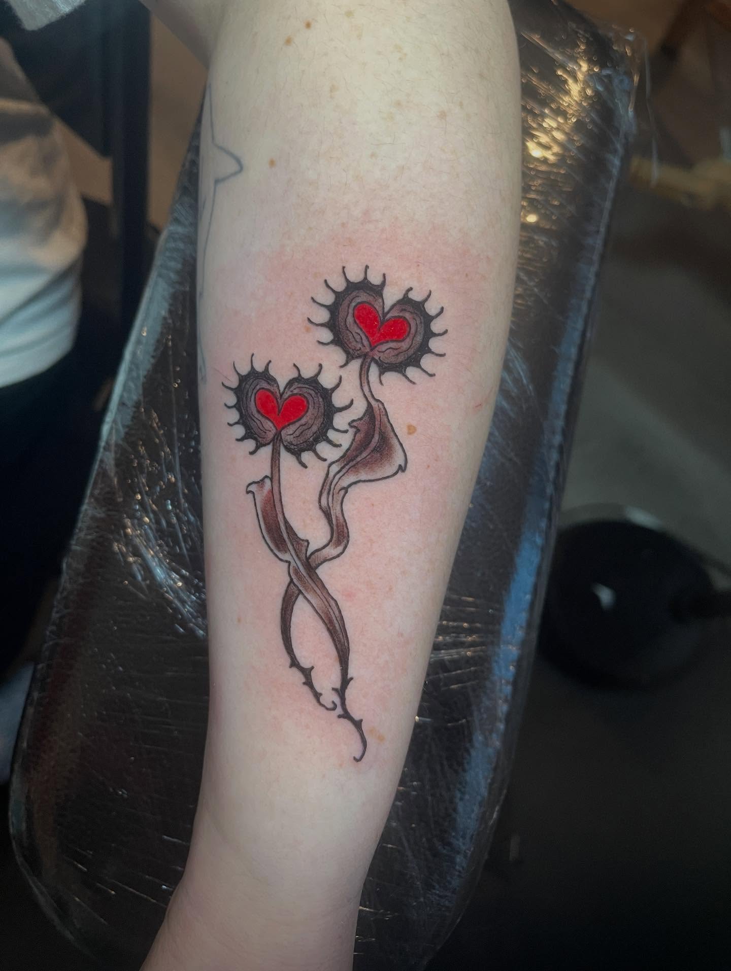Heart-shaped flowers neo-traditional tattoo on the forearm by Joe Moreira