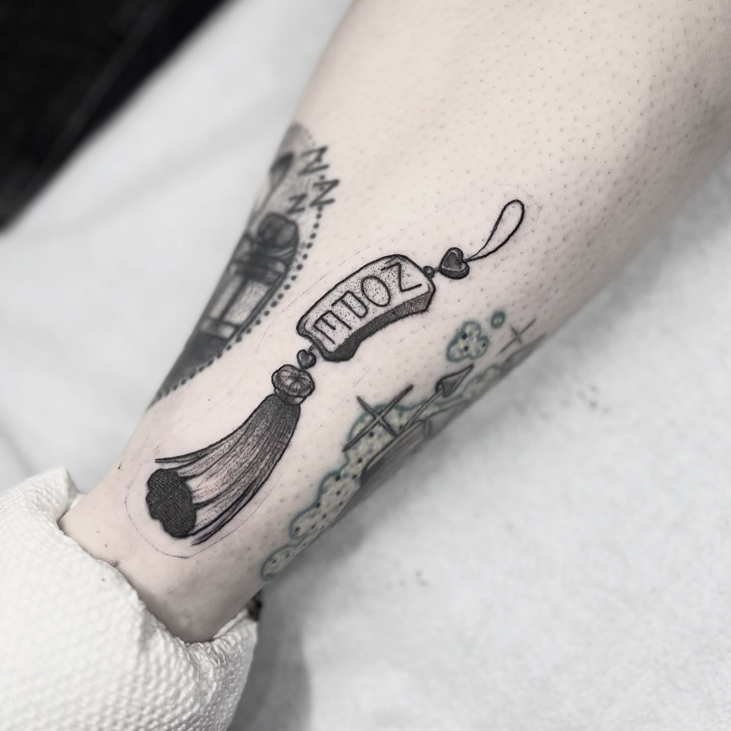 Scroll and tassel black and grey tattoo on the forearm by Alex Santaloci