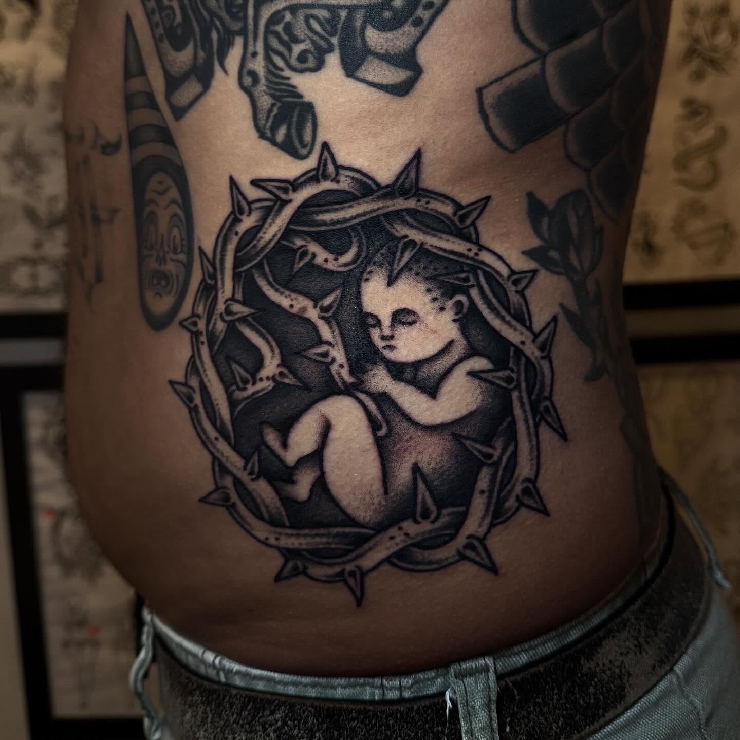 Child in thorns black and grey tattoo on the torso by Julia Louise