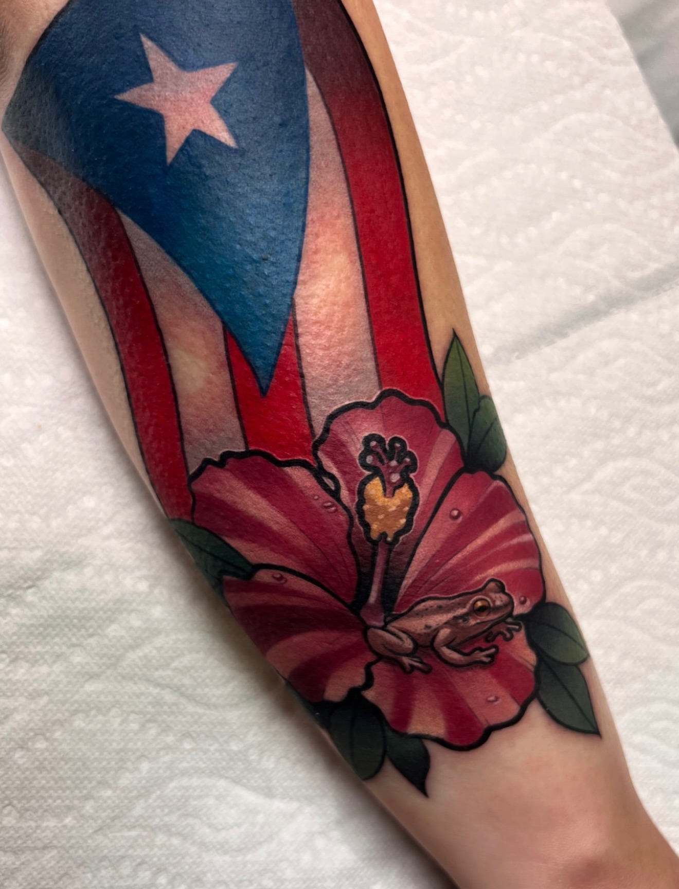 Puerto Rican flag and hibiscus flower American traditional tattoo on the forearm by Jake lyon