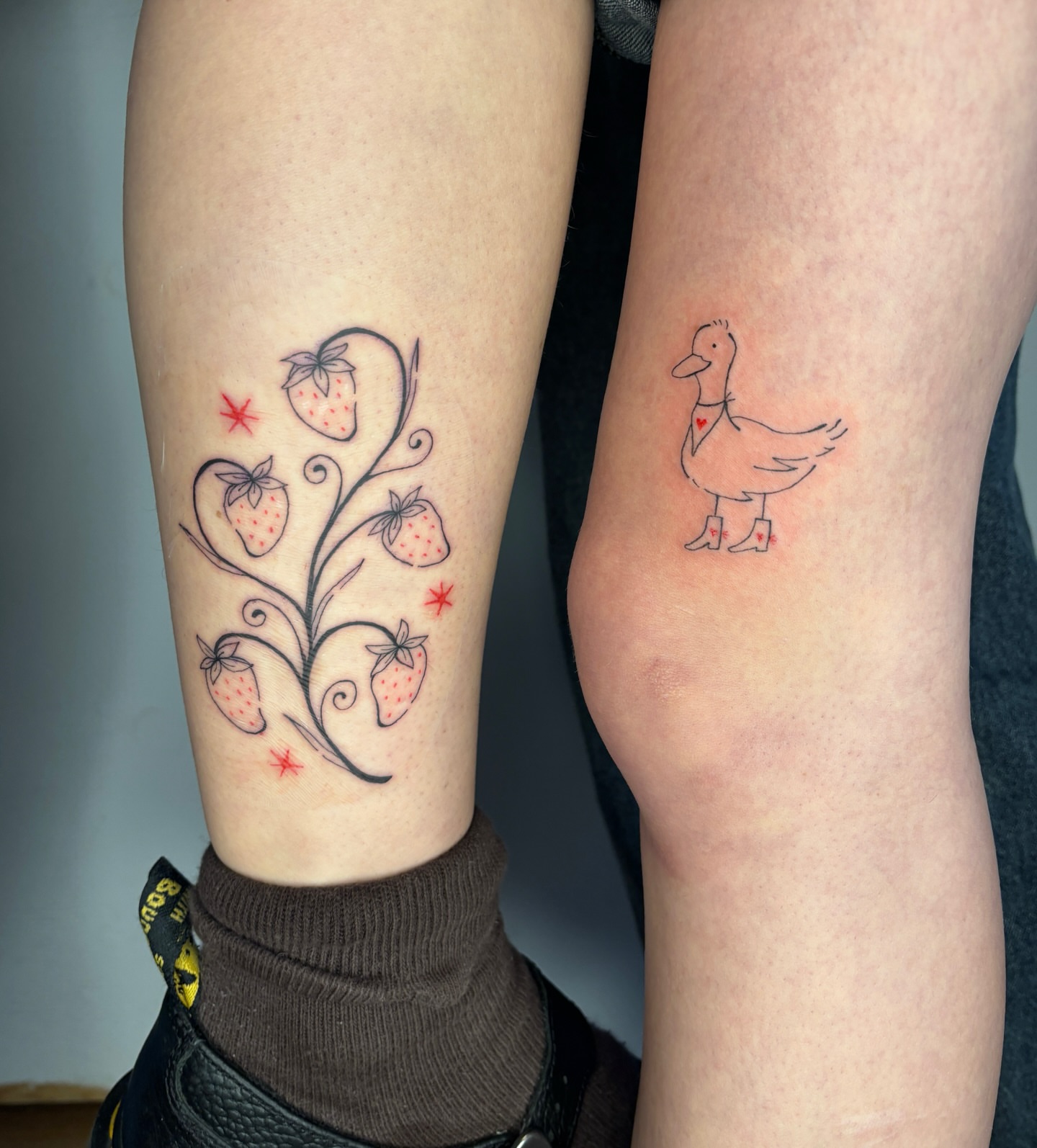 Strawberry plant and duck fine line tattoo on the forearm by Raye
