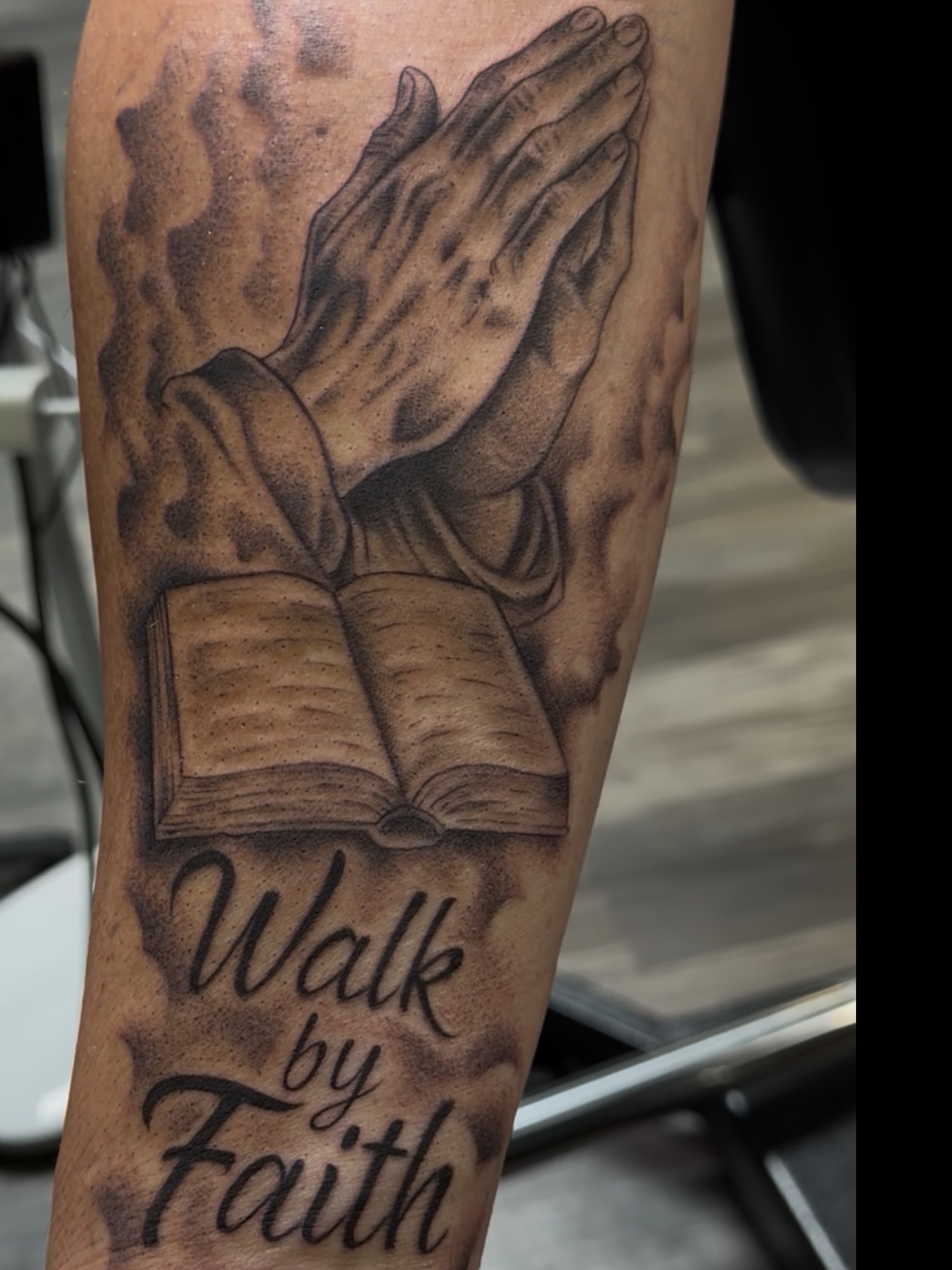 Praying hands and open book realism tattoo on the forearm by Jericho Las Vegas tattoo artist, Las Vegas, Nevada