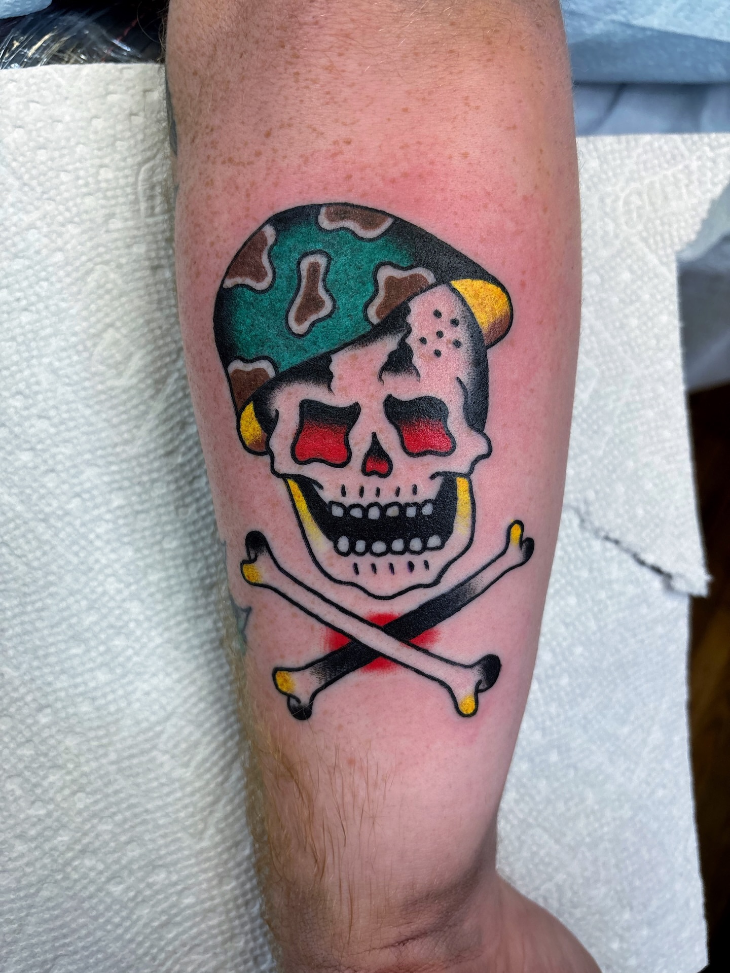 Skull and crossbones American traditional tattoo on the forearm by Cooper Reichwein