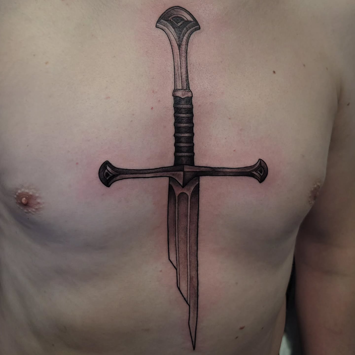 Sword black and grey tattoo on the chest by Marina Cobb