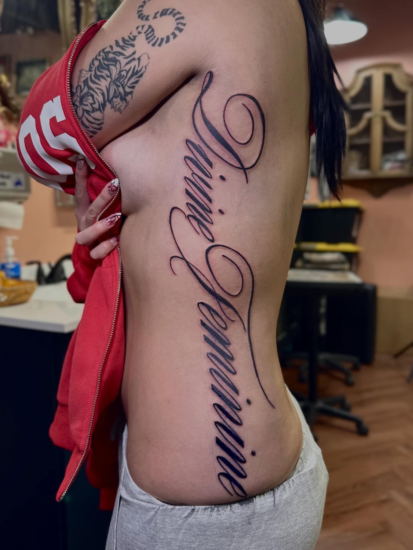 Script lettering lettering script tattoo on the ribs by Mathilda Quynh