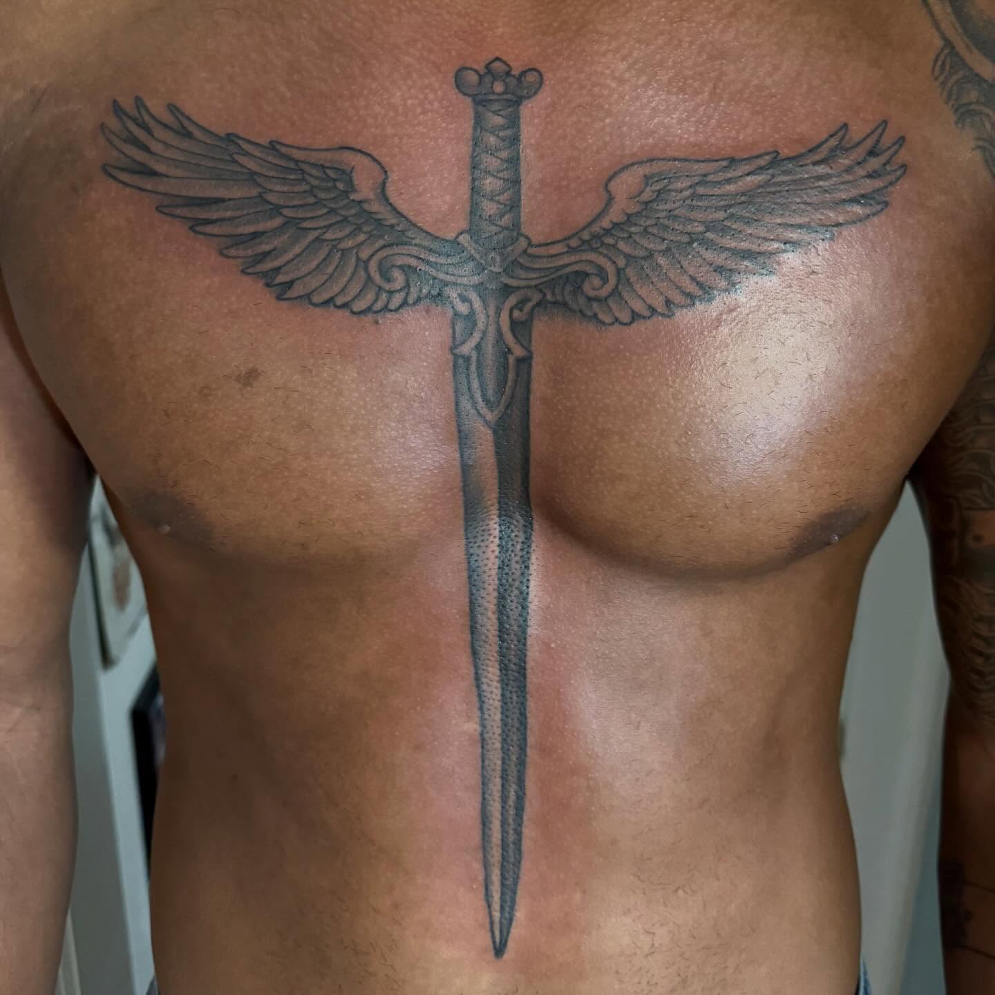 Winged sword dotwork tattoo on the chest by Tony Beuke