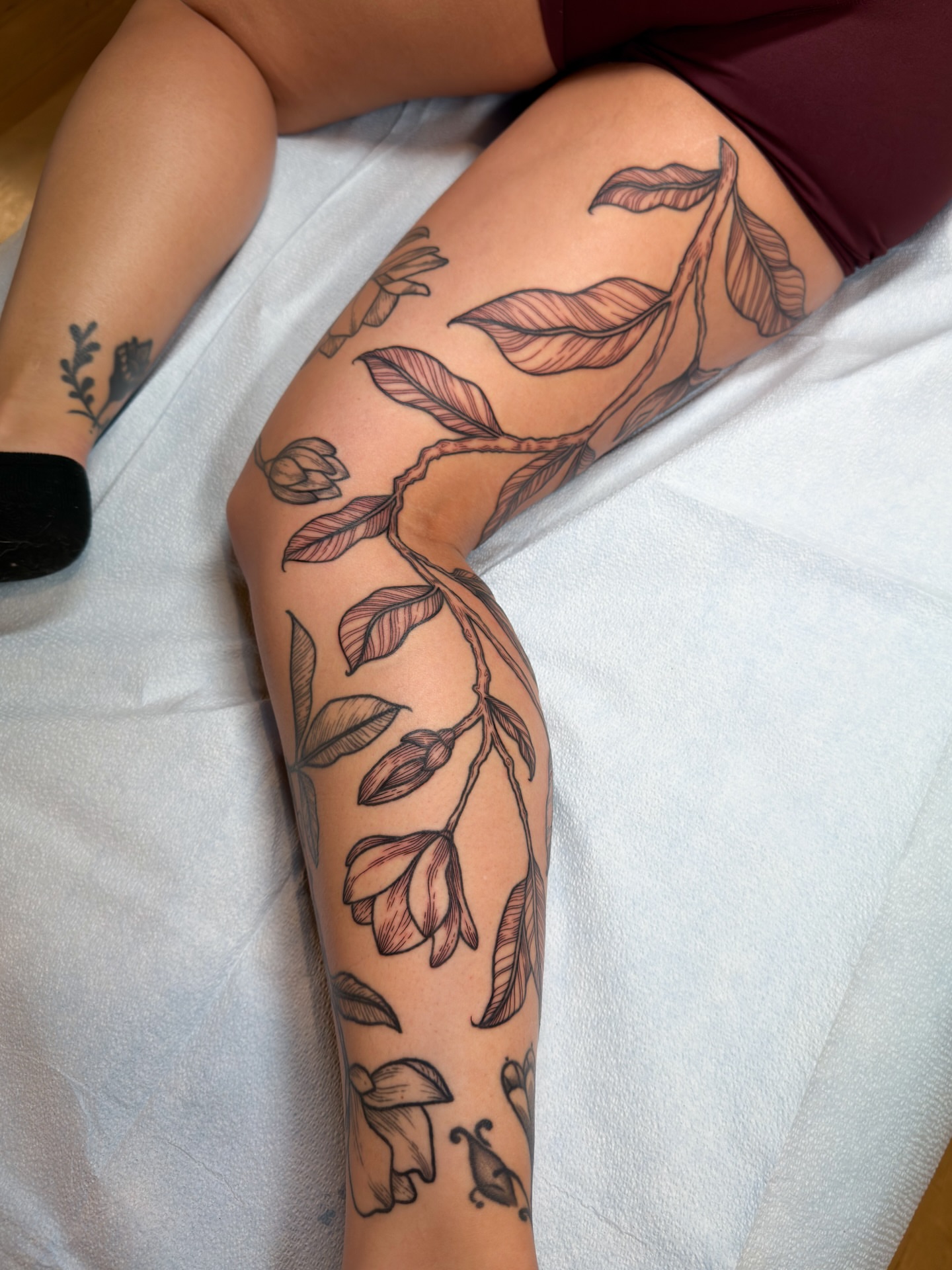 Botanical black and grey tattoo on the thigh by Alexandra Gray