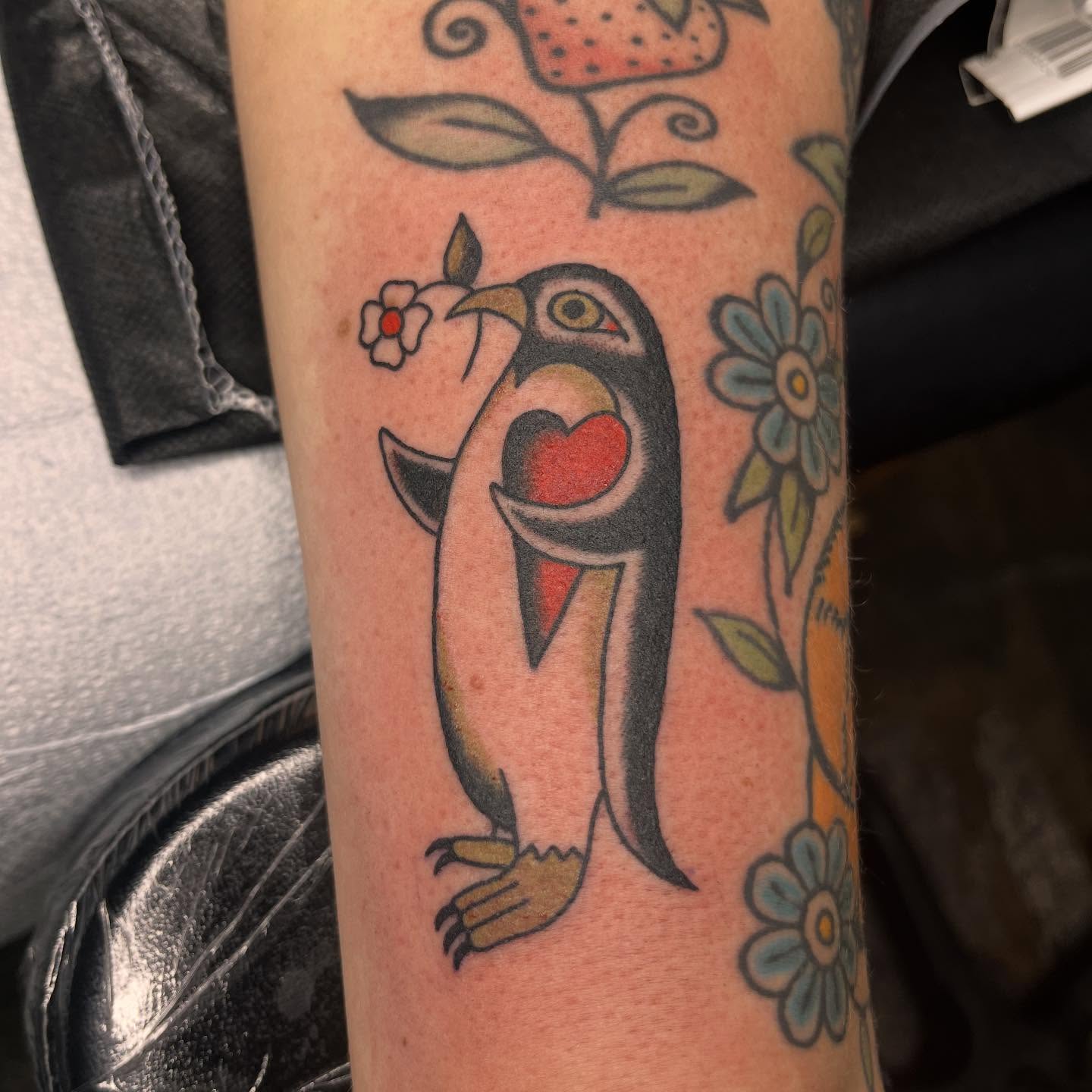 Penguin holding heart American traditional tattoo on the forearm by Nicole💀, Salt Lake City, Utah