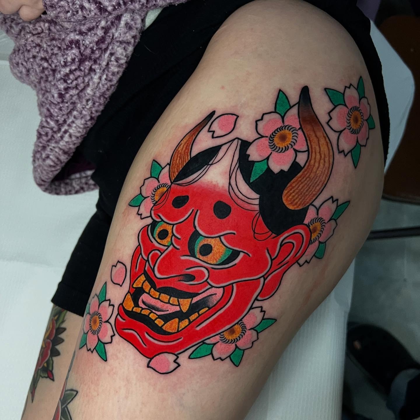 Demon mask with flowers American traditional tattoo on the thigh by doodle