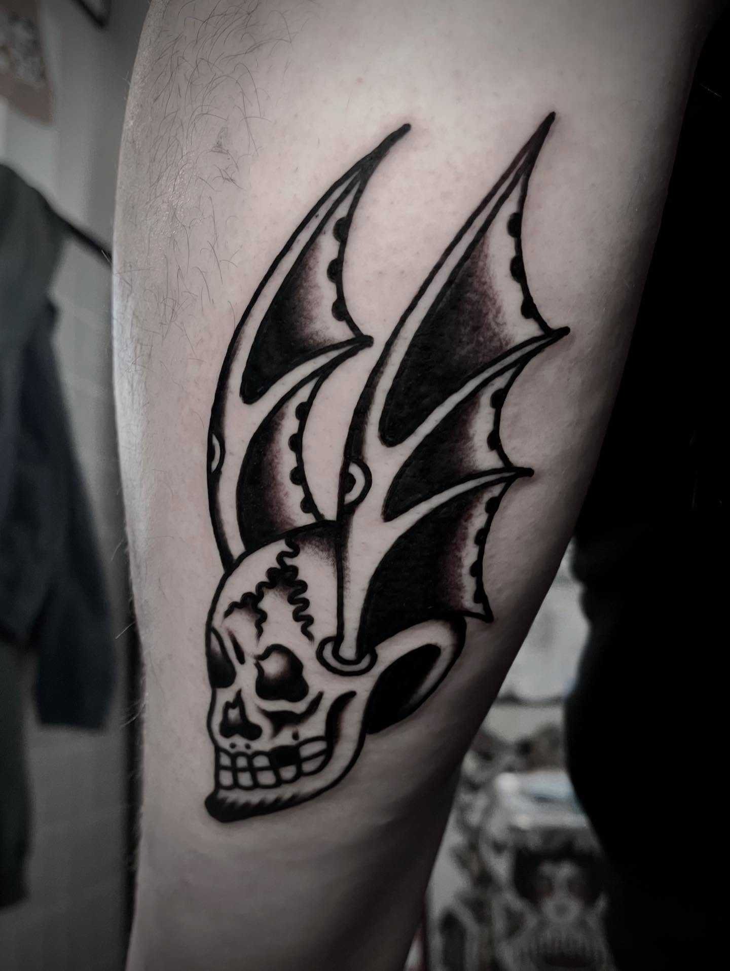 Skull with wings black and grey tattoo on the forearm by JohnJohn
